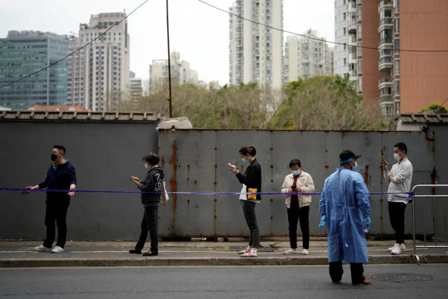 People practice social distancing as they line up behind a cordon to buy food, following the coronavirus disease (COVID-19) outbreak in Shanghai, China March 30, 2022. REUTERS/Aly Song