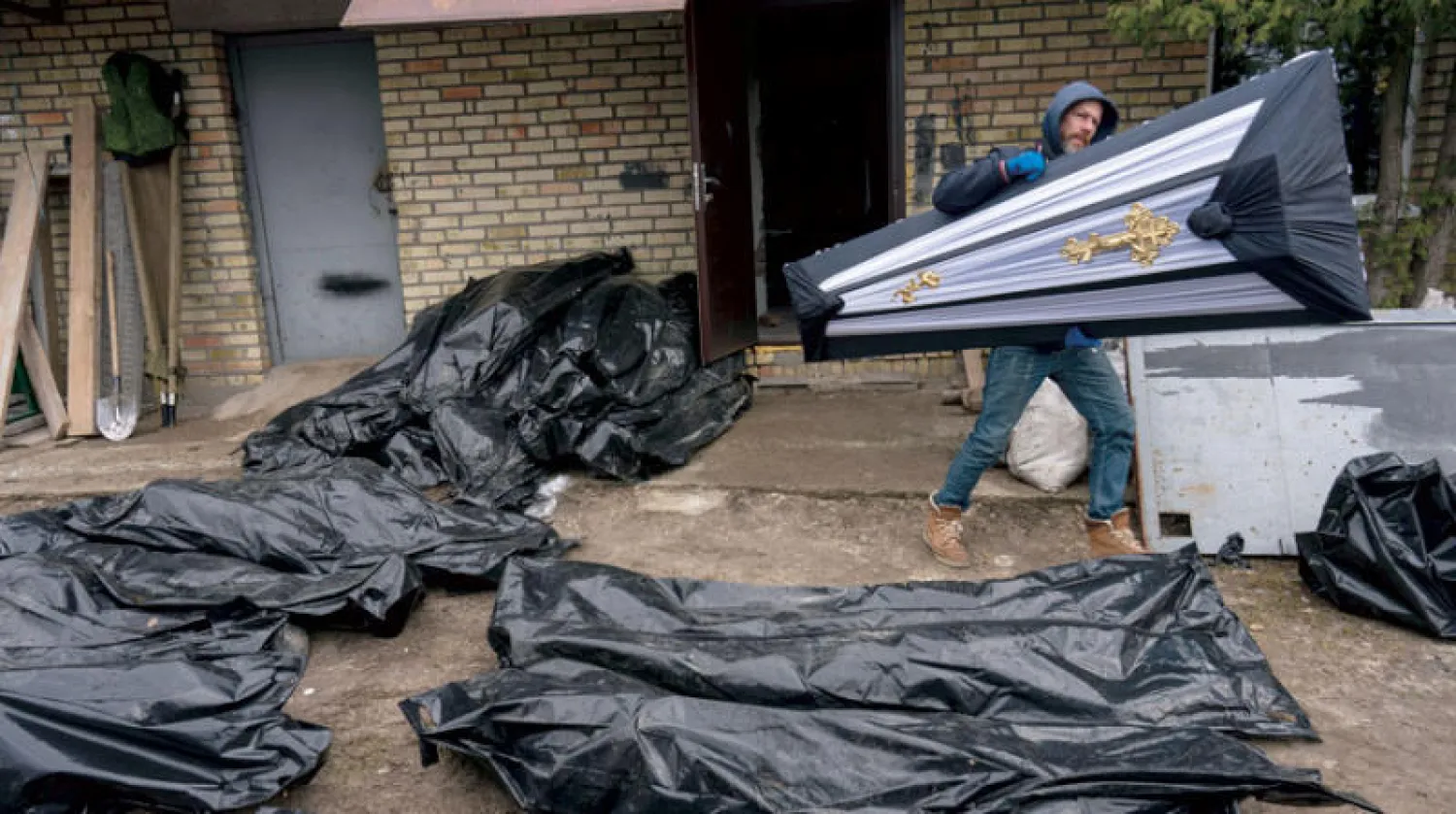 في بوتشا يحضرون الأكفان لنقل الجثث إلى ثلاجات الموتى (أ.ب)