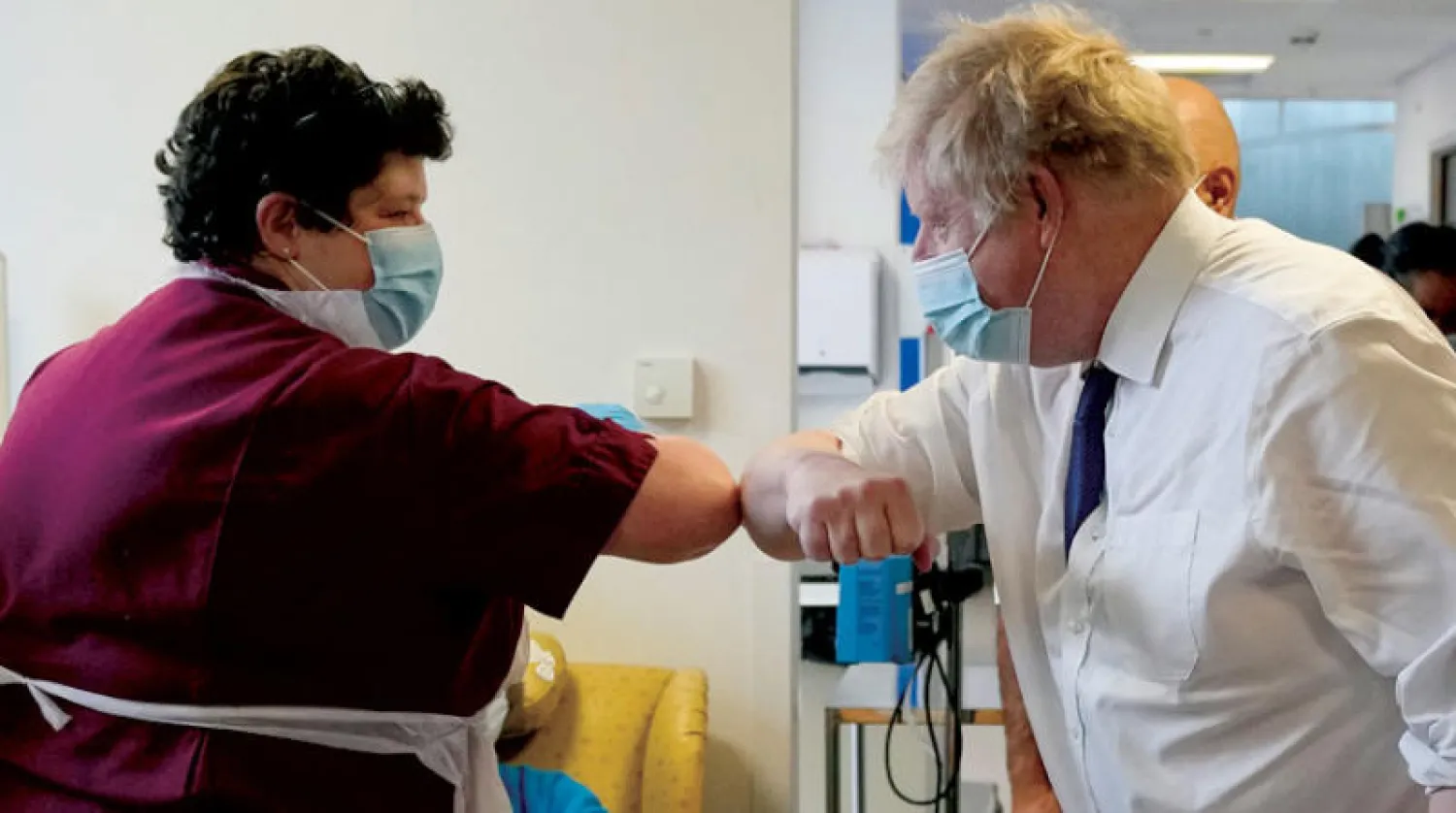 جونسون يحيي أحد أعضاء فريق التمريض خلال زيارة إلى مستشفى الملكة إليزابيث الثانية في شمال لندن الأربعاء الماضي (رويترز)