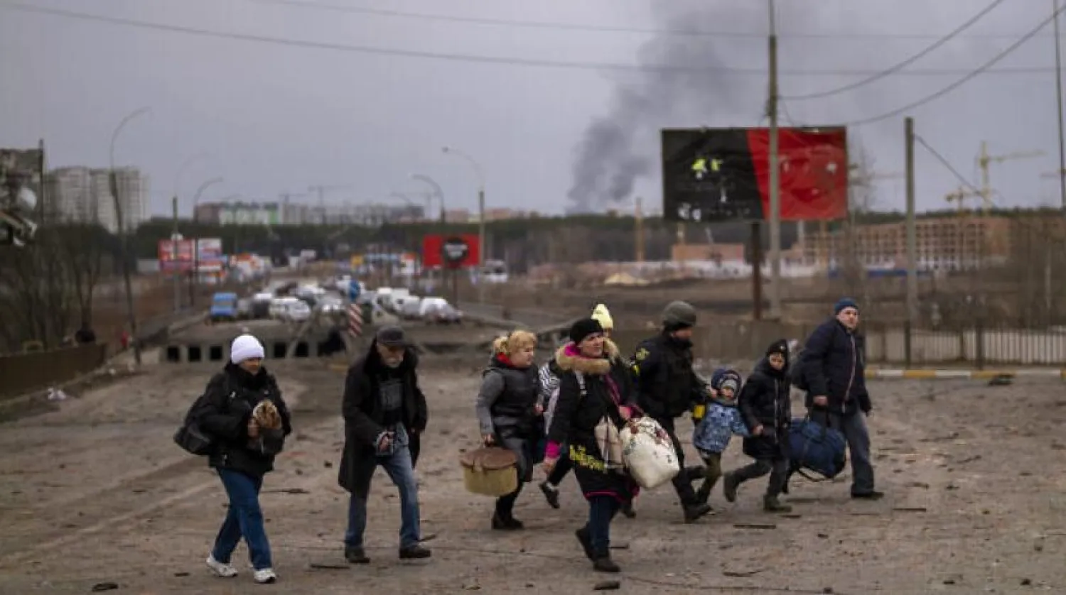 A Ukrainian police officer helps people as artillery echoes nearby while fleeing Irpin in the outskirts of Kyiv, Ukraine, March 7, 2022. (AP Photo/Emilio Morenatti)
