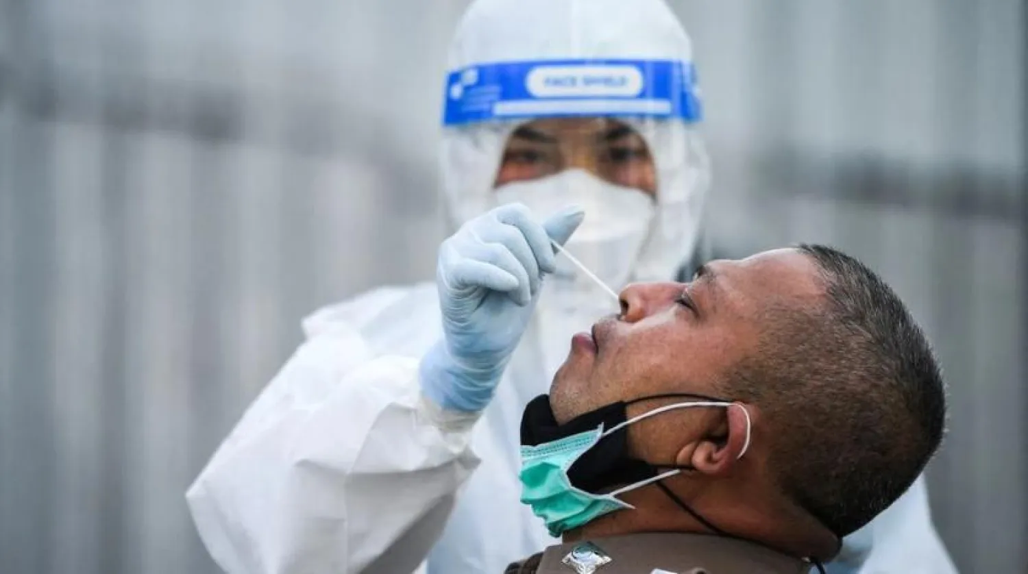 A health worker in personal protective equipment (PPE) takes a swab sample from a police officer for a rapid antigen test amid the coronavirus disease (COVID-19) outbreak, in Bangkok, Thailand, January 7, 2022. (Reuters)
