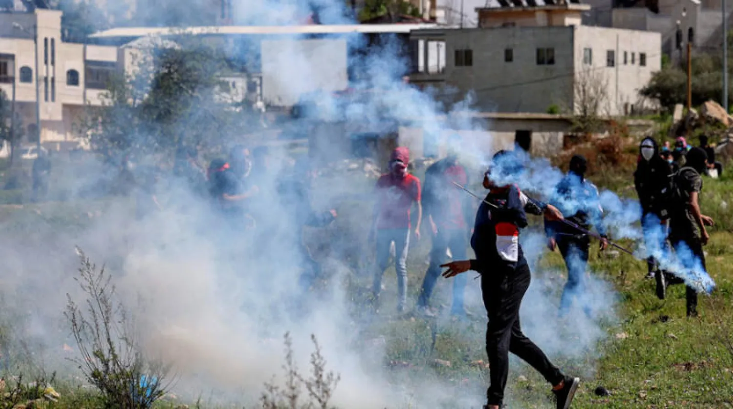 فلسطيني يعيد عبوة غاز مسيل للدموع باستخدام مقلاع خلال مواجهات مع قوات الأمن الإسرائيلية عند المدخل الشمالي لرام الله، (أ ف ب )