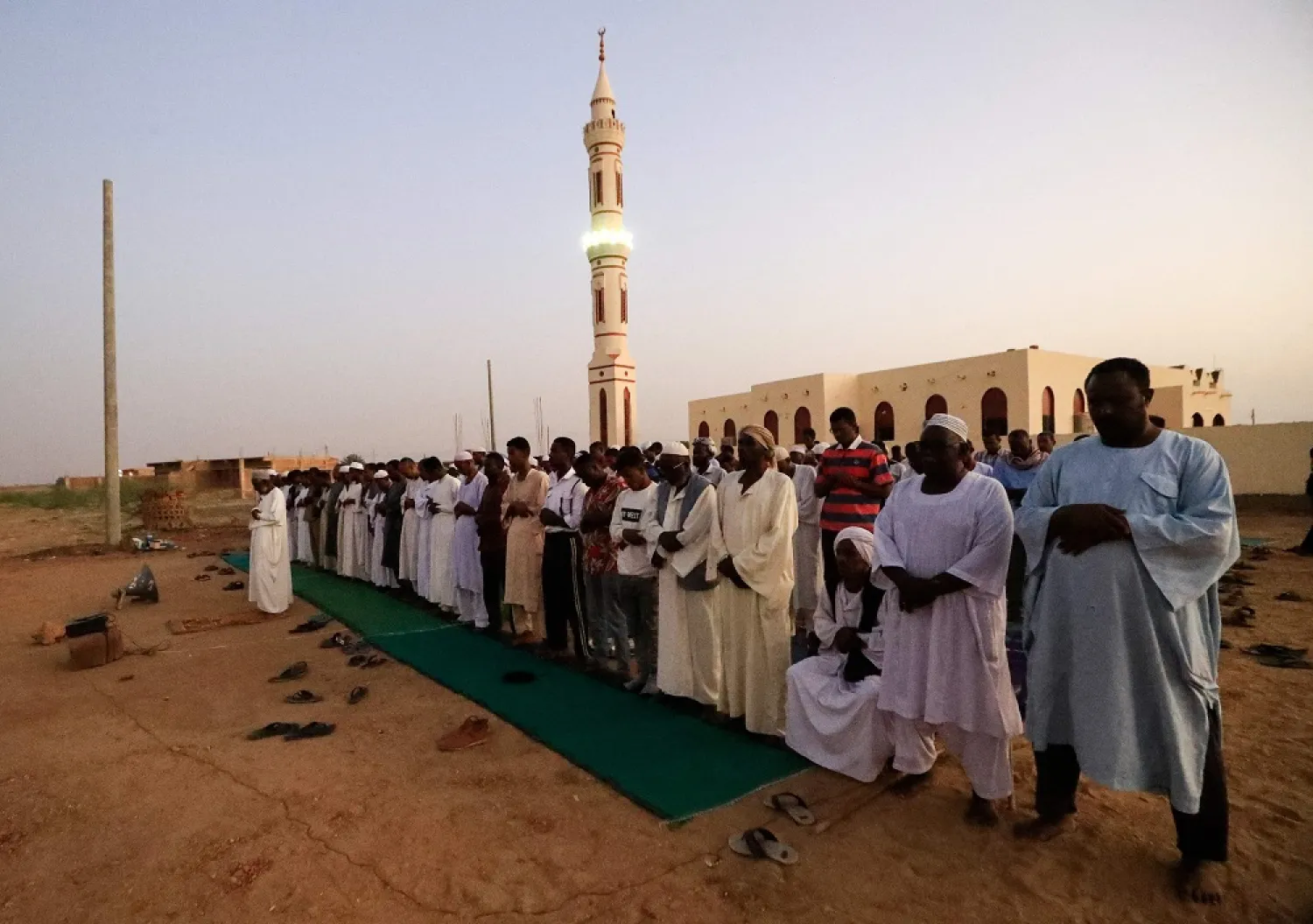 Men perform the sunset prayer before breaking their fast with a collective Iftar meal in front of a mosque along the Jazeera State highway in the village of al-Nuba, about 50 kilometers south of Sudan's capital, on April 8, 2022, during the Muslim holy month of Ramadan. (AFP)