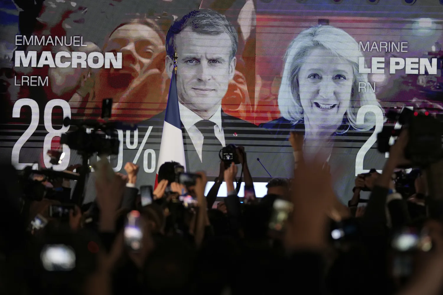 A screen shows French President Emmanuel Macron and centrist candidate for reelection and far-right candidate Marine Le Pen at her election day headquarters, in Paris, Sunday, April 10, 2022. (AP Photo/Francois Mori)
