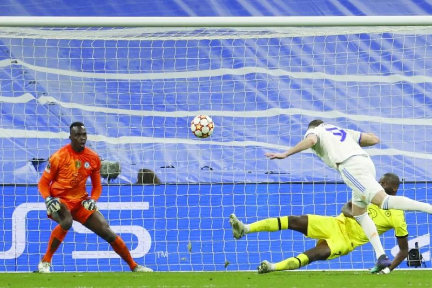 بنزيمة (يمين) يسجل برأسه هدف ريال مدريد الثاني ليحرم تشيلسي من المرور إلى نصف النهائي (إ.ب.أ)