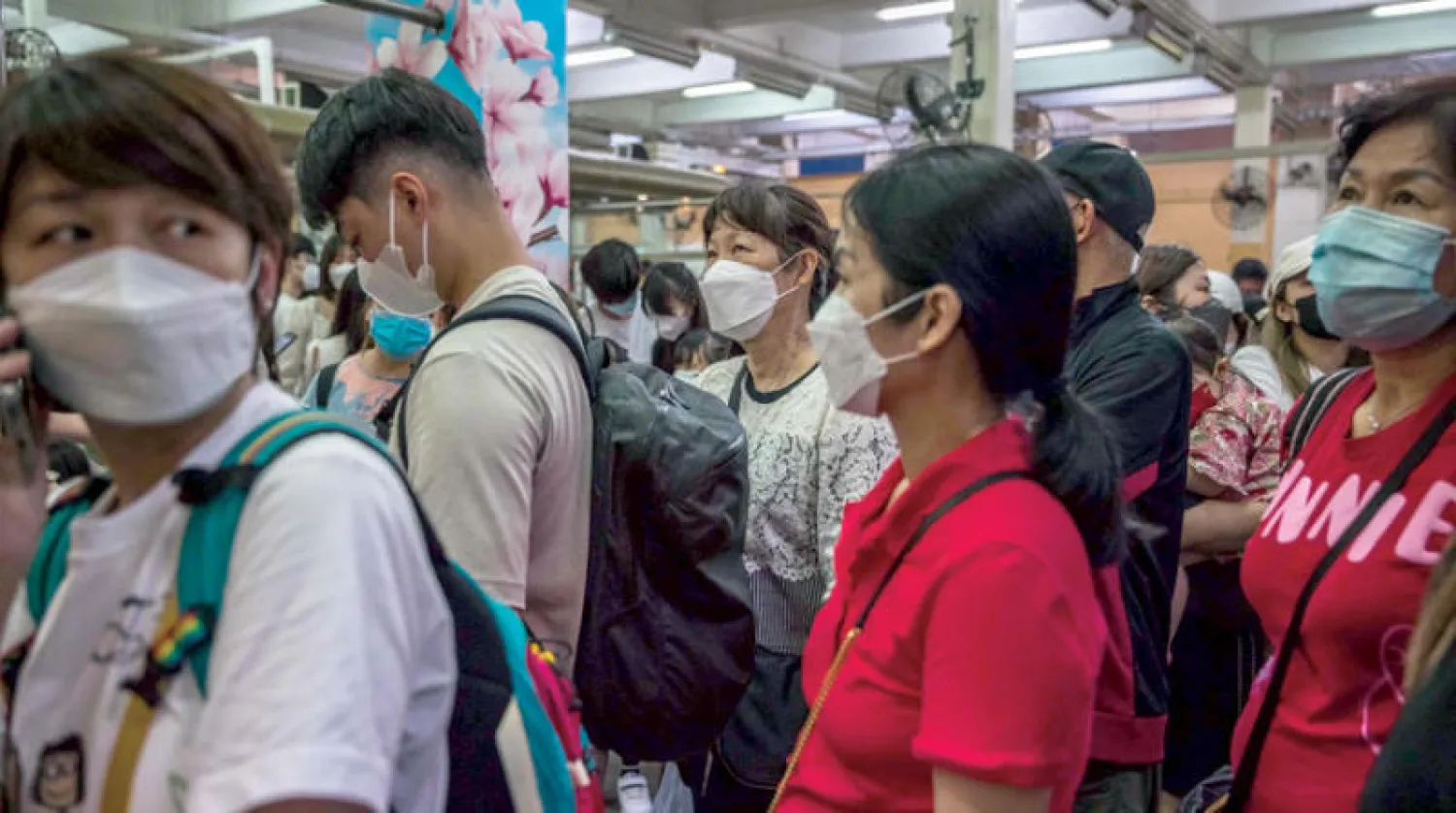 أشخاص يرتدون كمامات ينتظرون ركوب عبّارة في جزيرة تشونغ تشاو جنوب غرب هونغ كونغ أول من أمس (أ.ف.ب)