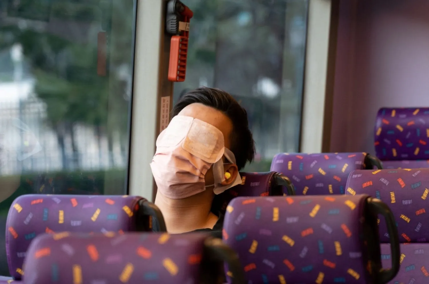 A passenger sleeps on a bus operated by a Hong Kong travel agency offering a five-hour "quiet bus" tour marketed as a "route to nowhere" for travel-craving and restless residents to snooze on board in Hong Kong, Nov. 14, 2021. (AFP Photo)