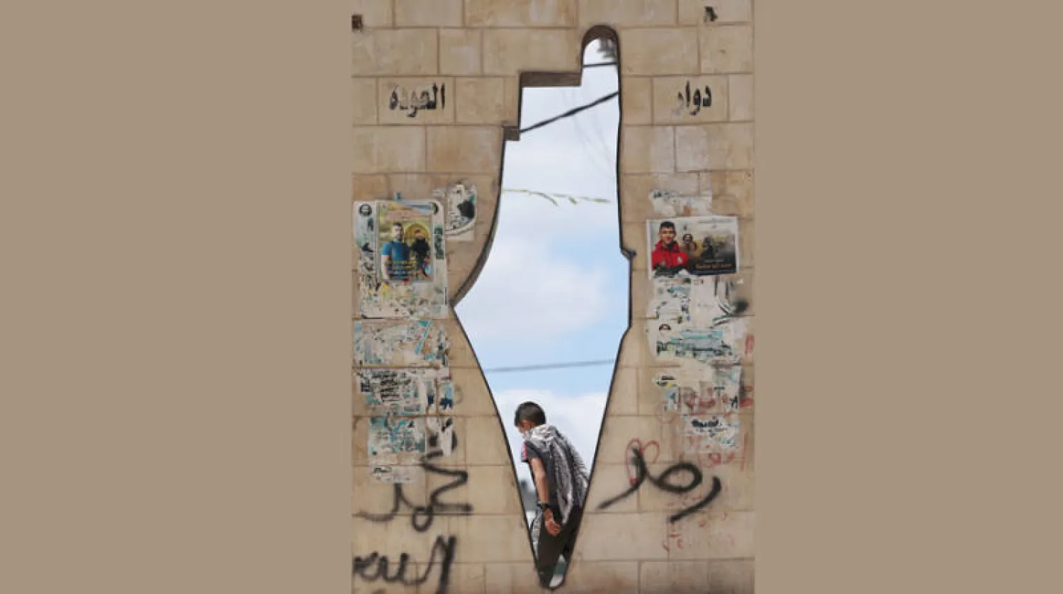 طفل فلسطيني يمر داخل معلم تذكاري لخريطة لفلسطين الانتدابية في بلدة جنين بالضفة (أ.ف.ب)