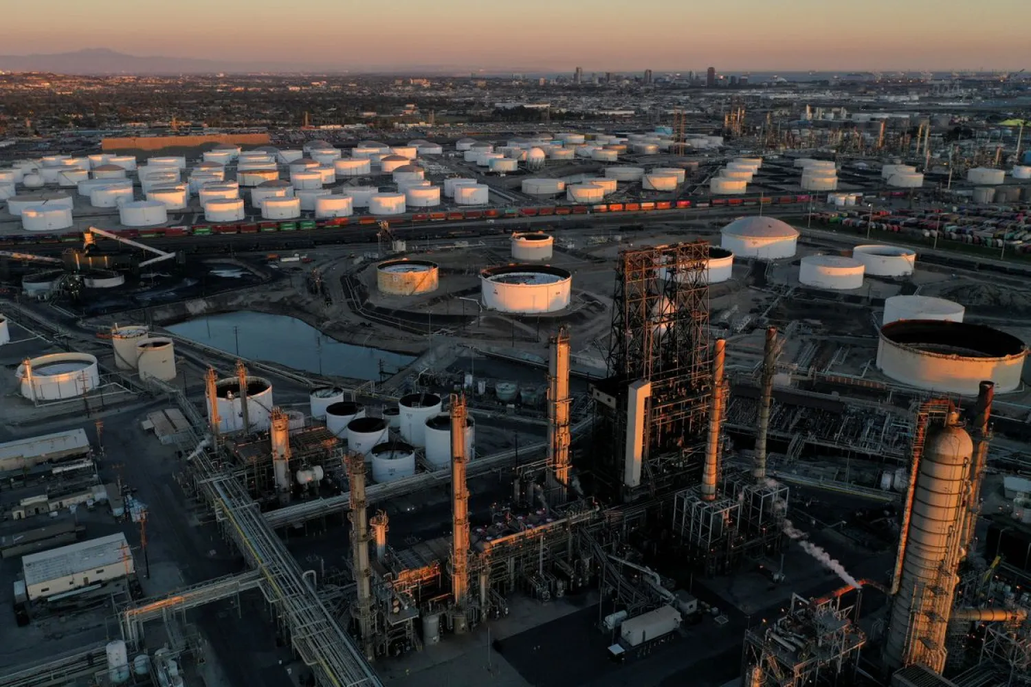 A view of the Phillips 66 Company's Los Angeles Refinery (foreground), which processes domestic & imported crude oil into gasoline, aviation and diesel fuels, and storage tanks for refined petroleum products at the Kinder Morgan Carson Terminal (background), at sunset in Carson, California, US, March 11, 2022. Picture taken with a drone. REUTERS/Bing Guan
