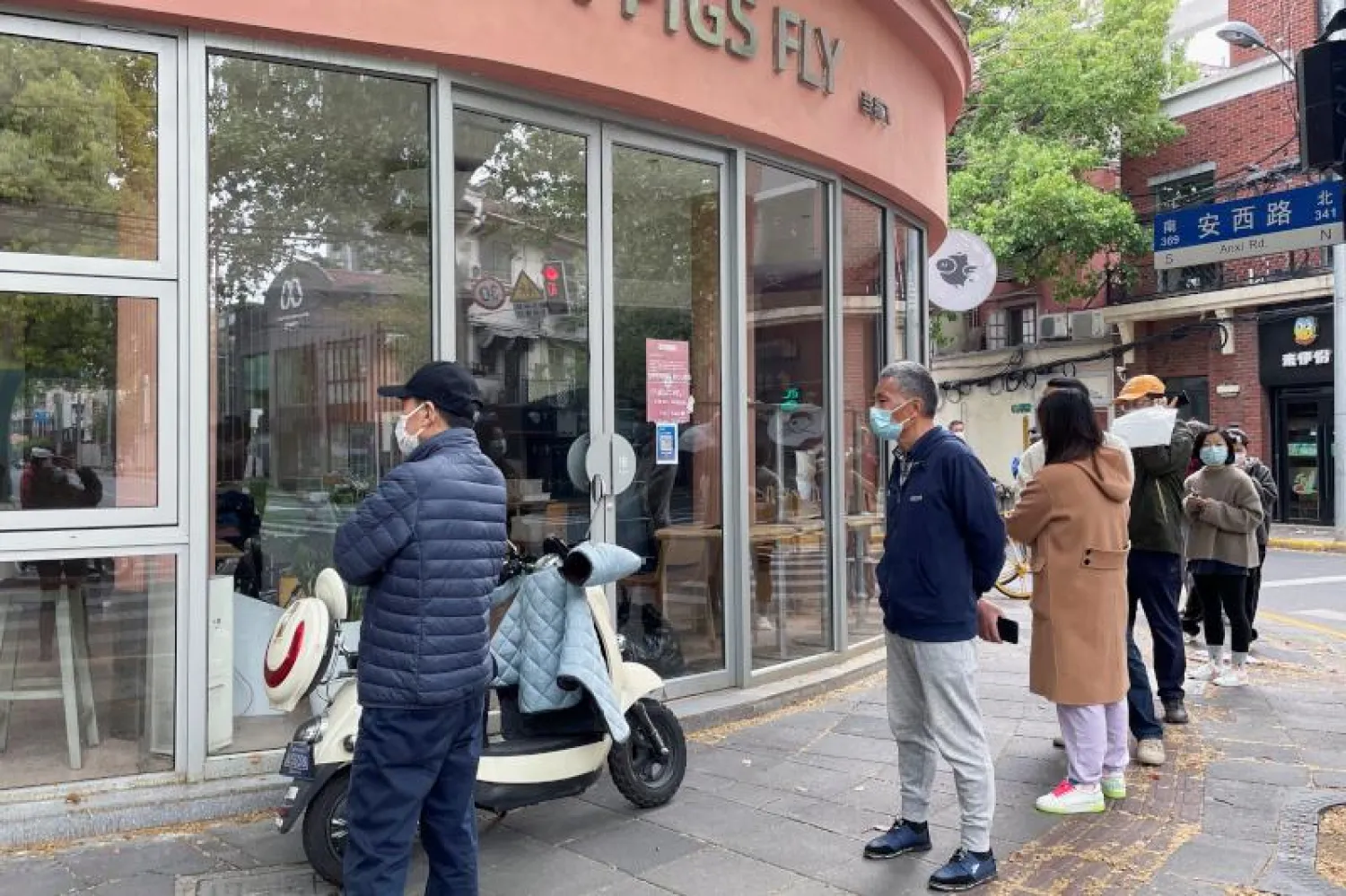 صينيون ينتظرون خارج مخبز لشراء الخبز بعد تخفيف القيود نسبياً في شنغهاي (رويترز)