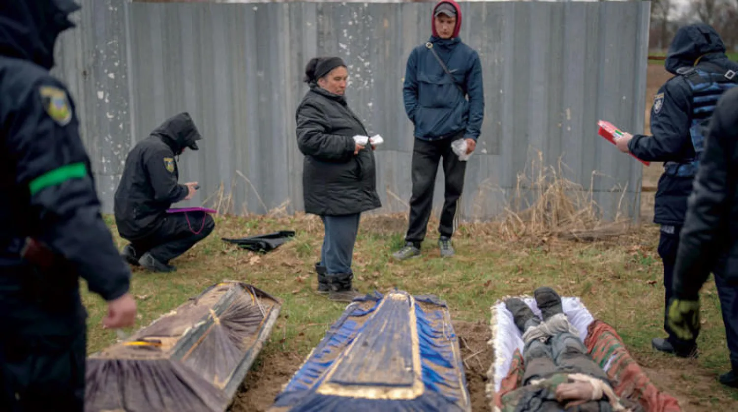 سكان قرية ميكوليتشي قرب كييف يتعرفون على بعض جثامين الضحايا (أ.ب)