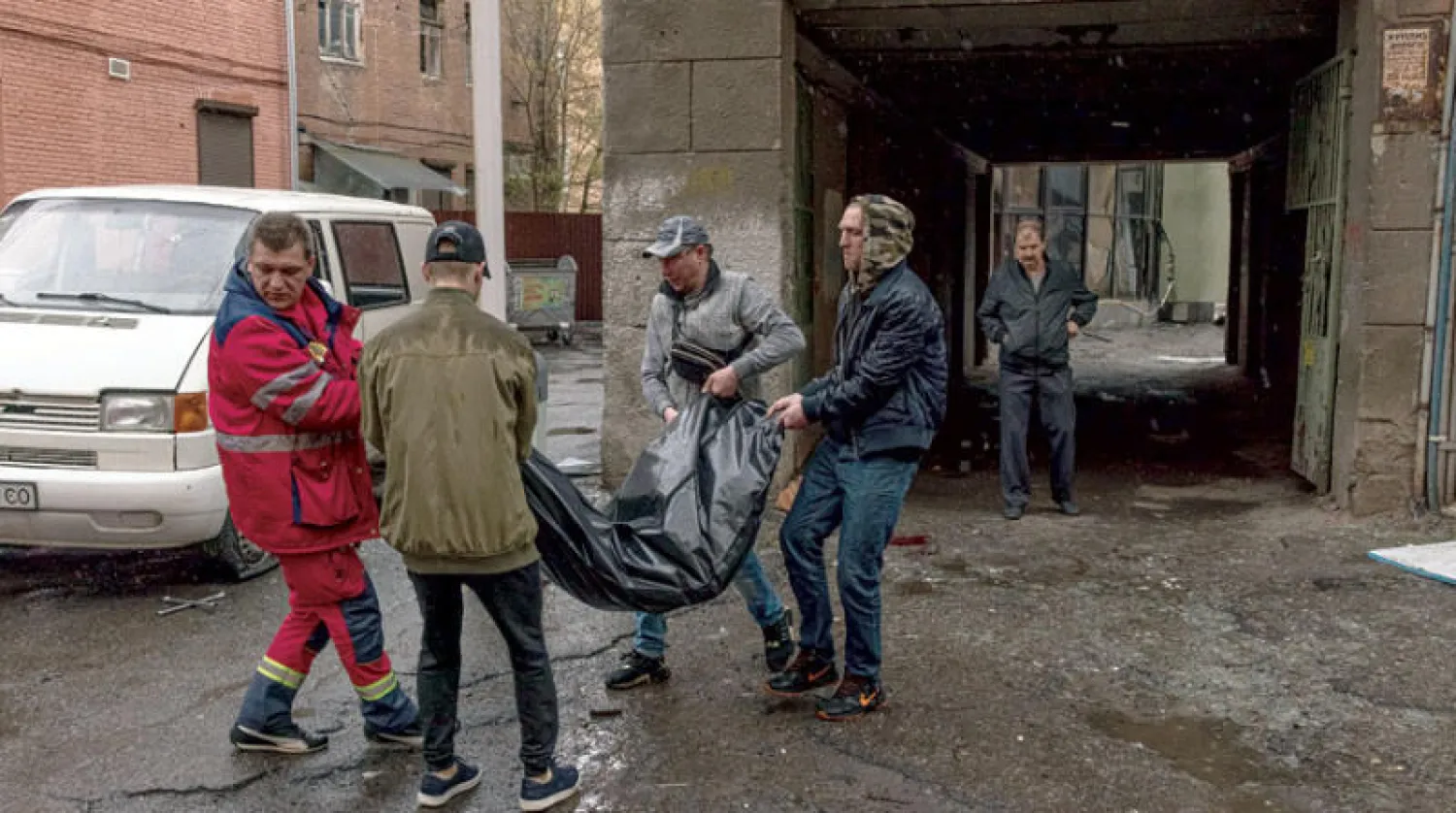 متطوعون ينقلون جثة مدني في مدينة خاركيف بشمال شرقي أوكرانيا أمس (إ.ب.أ)