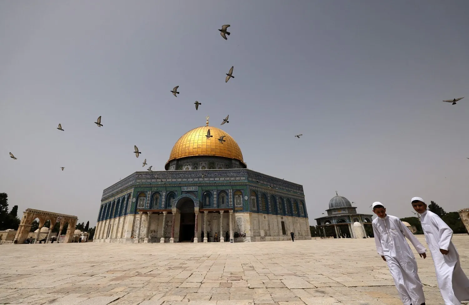 Palestinian Muslims walk in front of the Dome of Rock mosque at the al-Aqsa mosque compound in Jerusalem's Old City on April 17, 2022. (AFP)