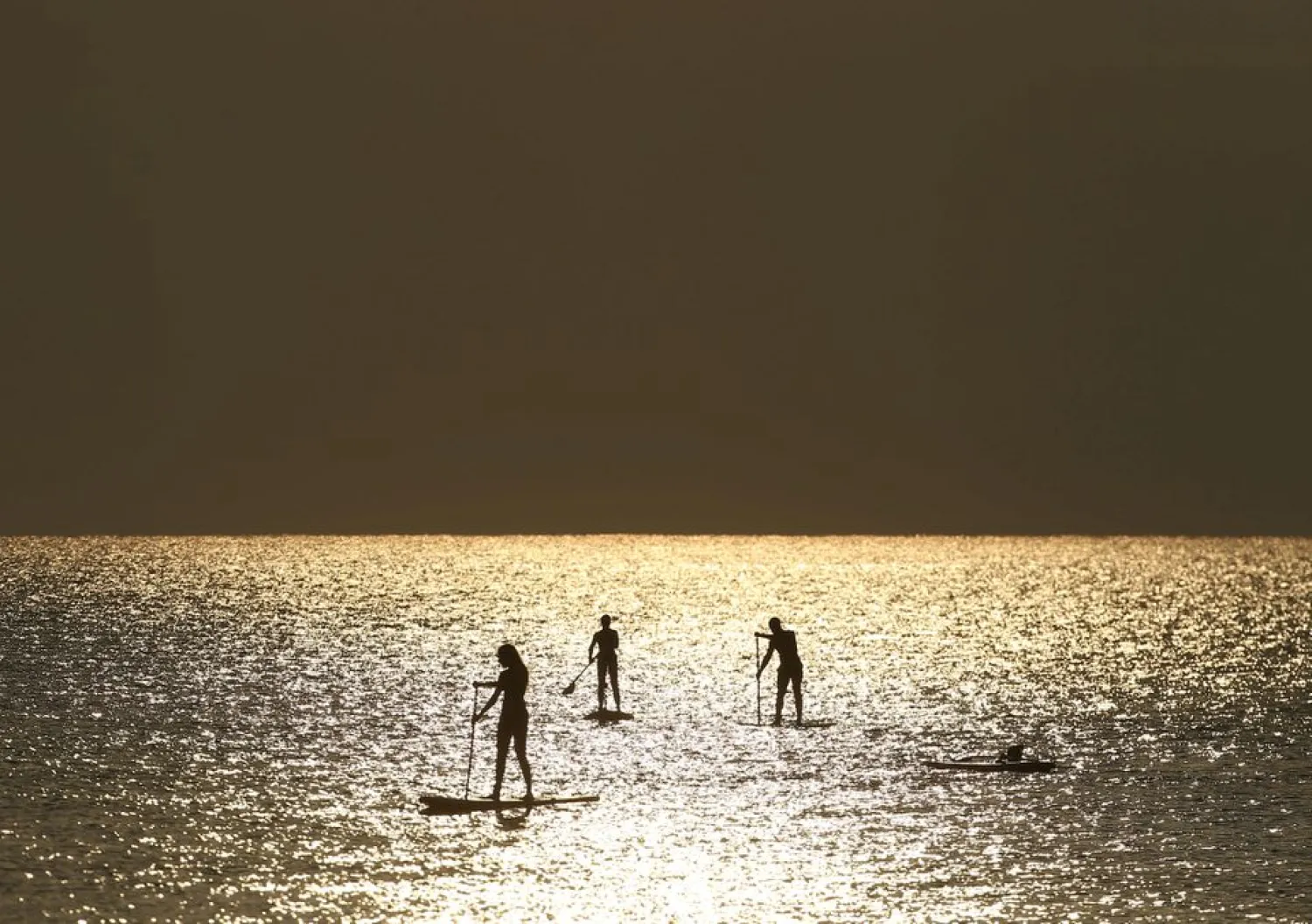 People paddle on a stand-up board during sunrise near a beach in Larnaca, Cyprus August 27, 2020. REUTERS/Yiannis Kourtoglou