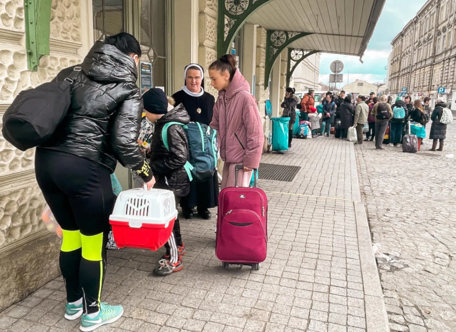 راهبة تقف بجانب أطفال اللاجئين الأوكرانيين بمحطة القطار في برزيميسل في بولندا (د.ب.أ)