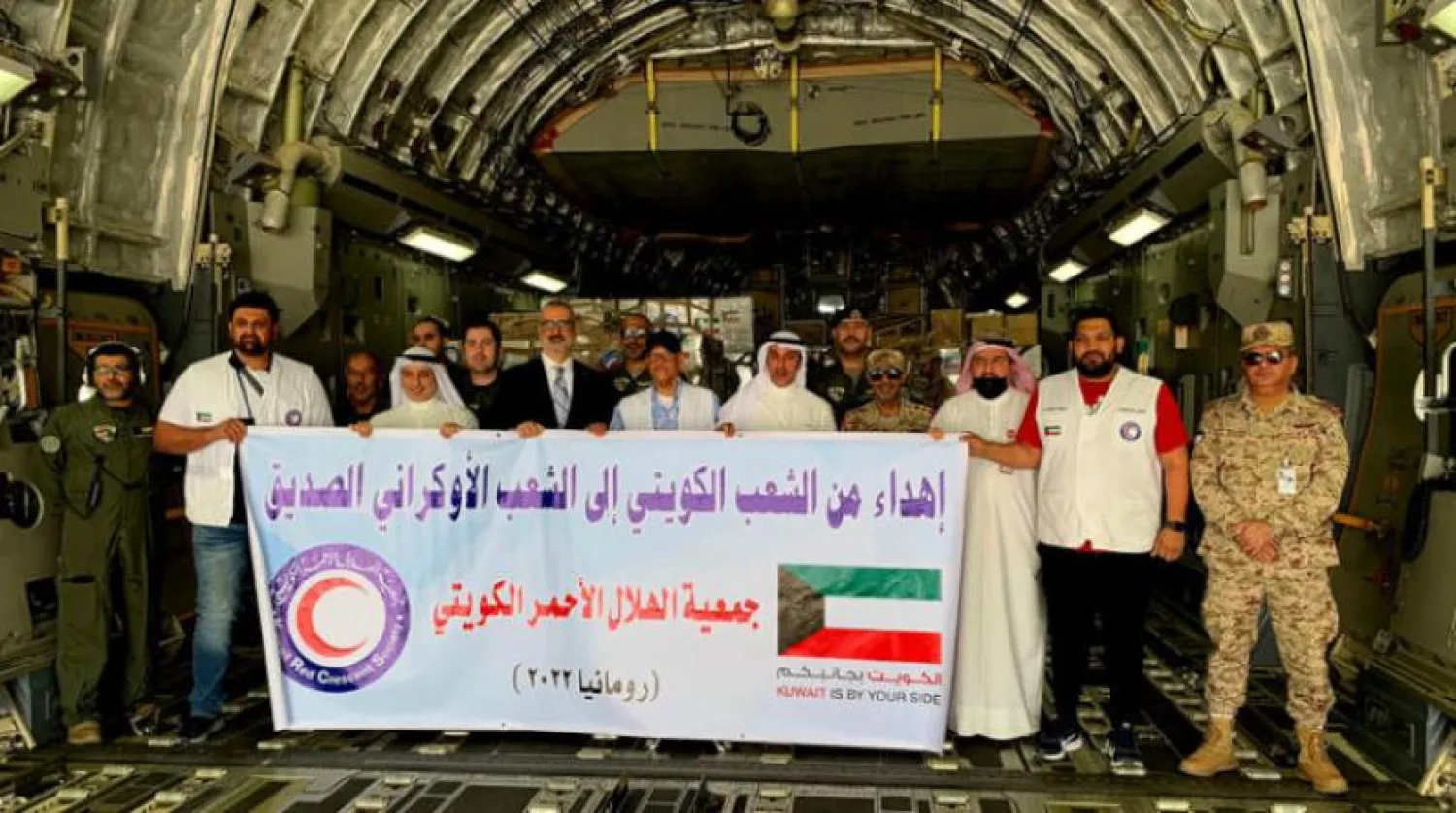 Officials pose for a group photo in front of a plane carrying aid to Ukrainian refugees that left Kuwait on Tuesday, April 19, 2022. (KUNA) 
