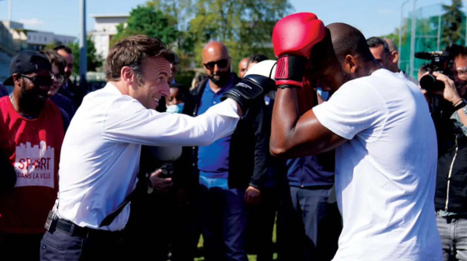 إيمانويل ماكرون يلاكم استعراضياً خلال وقفة انتخابية في ملعب رياضي بضواحي باريس أمس (رويترز)