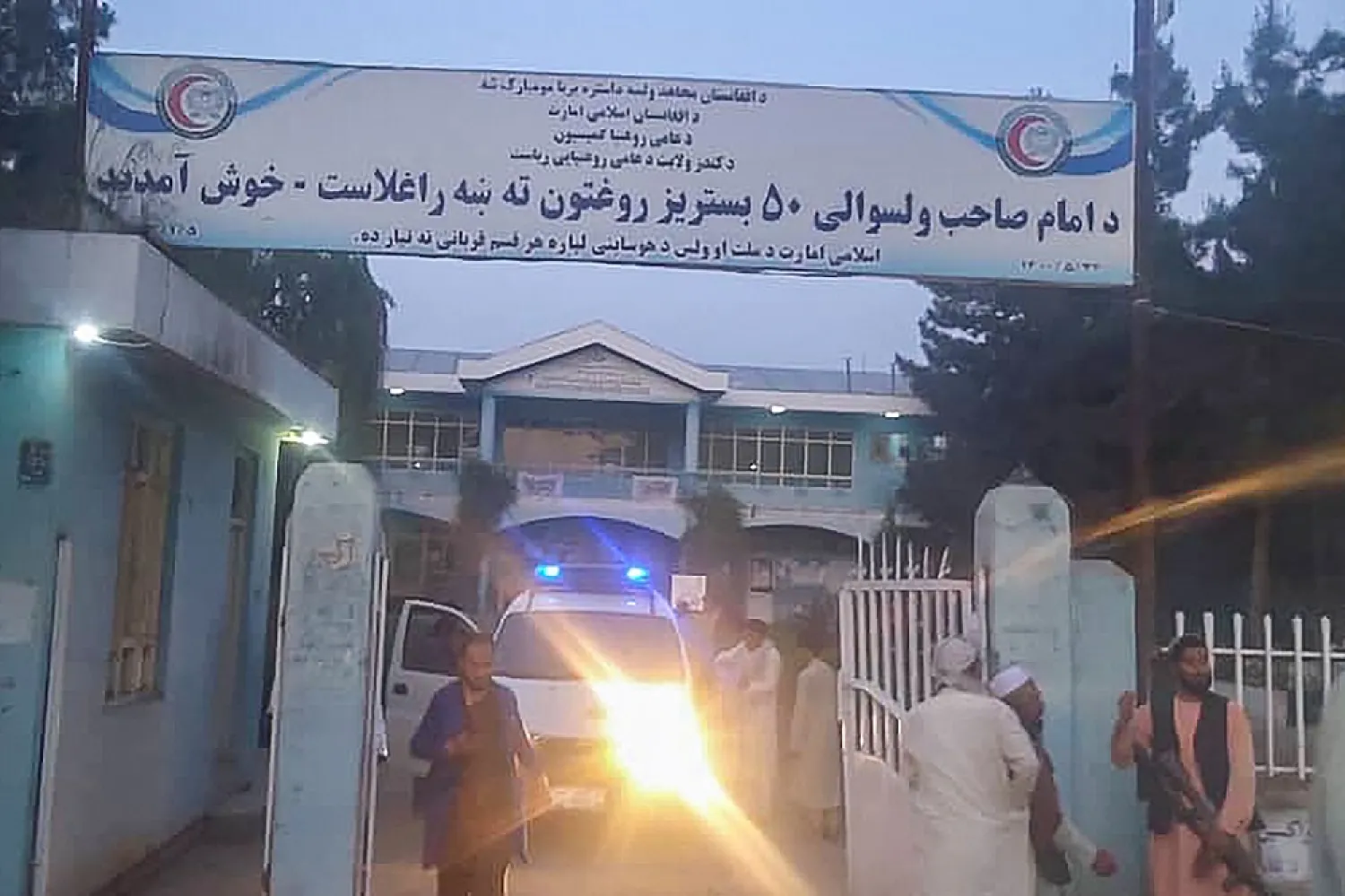 Taliban fighters and medical staff stand outside the gate of an hospital as they prepare to attend to the casualties after an explosion at Imam Sahib district in Kunduz province on April 22, 2022. (AFP)