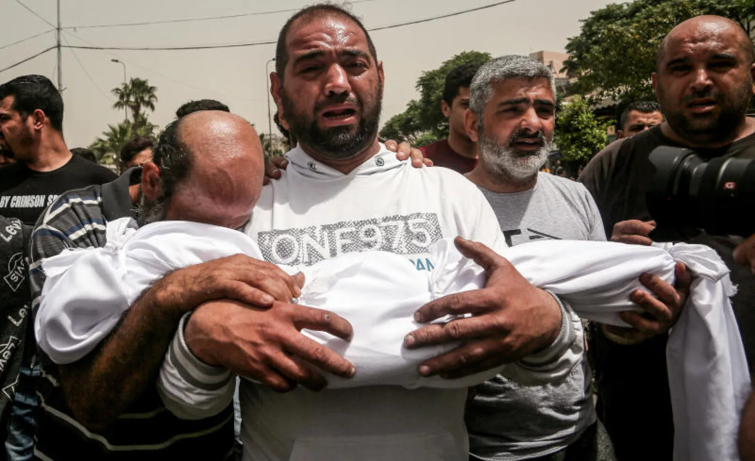 أحد أقارب طفلة لم تبلغ الرابعة قضت غرقاً في قارب الموت بطرابلس يحمل جثمانها خلال تشييع ضحايا الحادث (د.ب.أ)