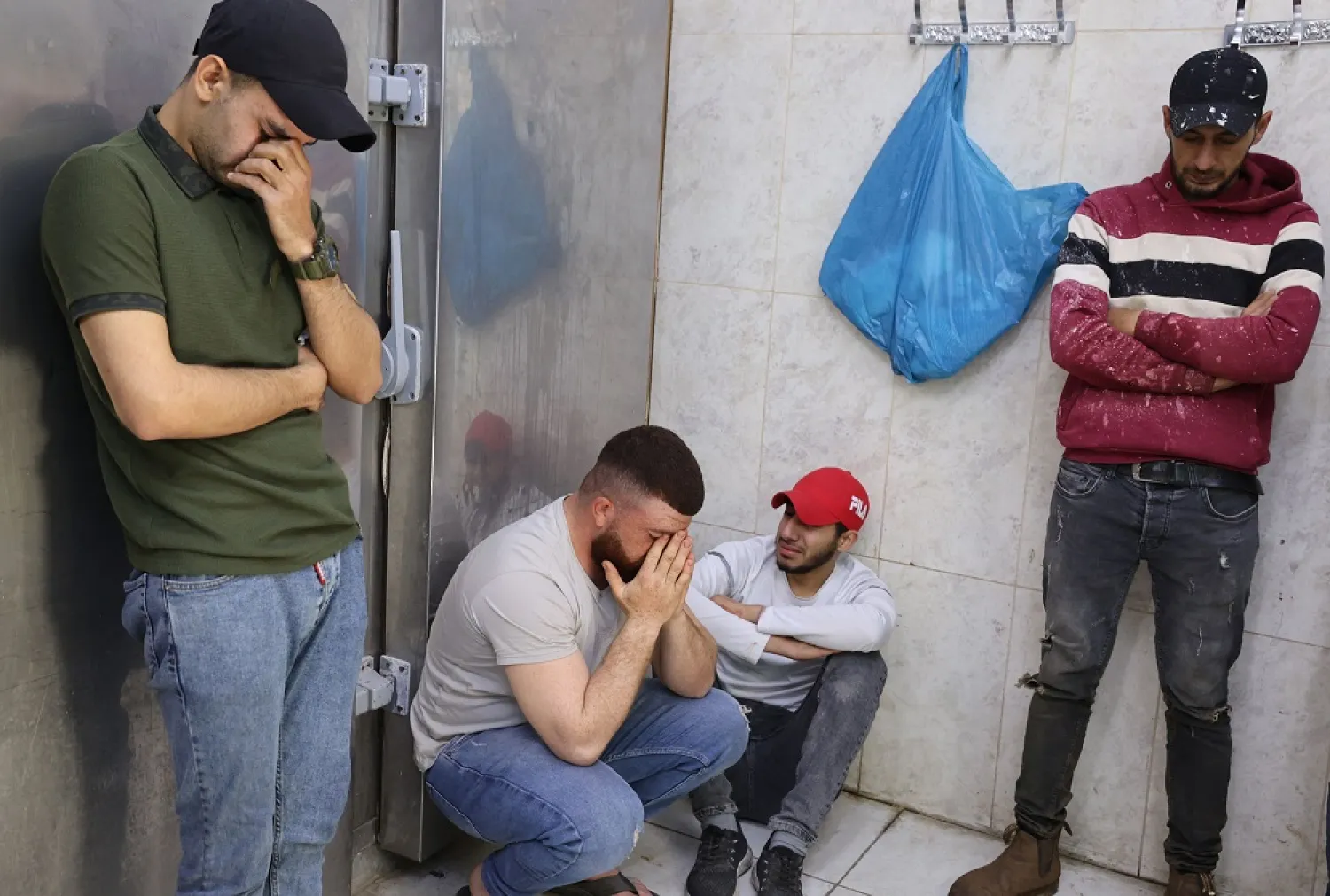 Palestinian men mourn at the morgue of a hospital in Jenin in the occupied West Bank on April 27, 2022. (AFP)