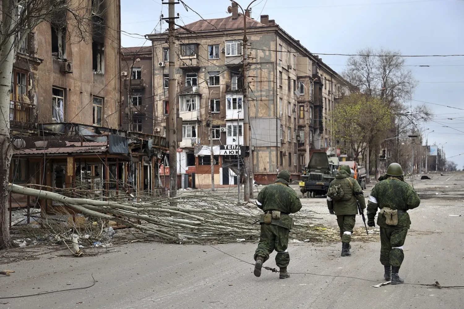 Servicemen of the militia from the Donetsk People's Republic walk past damaged apartment buildings near the Illich Iron & Steel Works Metallurgical Plant, the second-largest metallurgical enterprise in Ukraine, in an area controlled by Russian-backed separatist forces in Mariupol, Ukraine, Saturday, April 16, 2022. (AP)