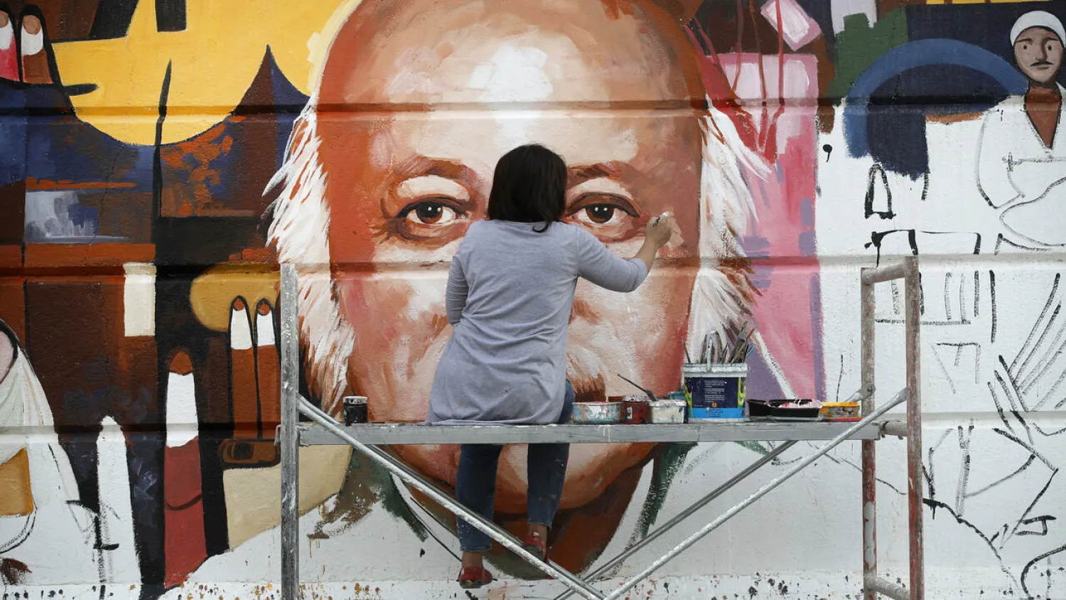 Perched on a scaffold at a busy intersection, 49-year-old Wijdan al-Majed adds final touches to a Baghdad mural dedicated to celebrated Iraqi poet Muzzafar al-Nawab AHMAD AL-RUBAYE AFP
