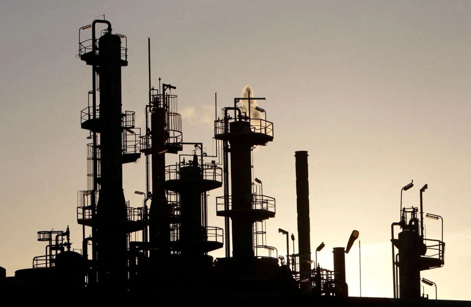 Towers and smokestacks are silhouetted at an oil refinery in Melbourne June 21, 2010. REUTERS/Mick Tsikas/File Photo