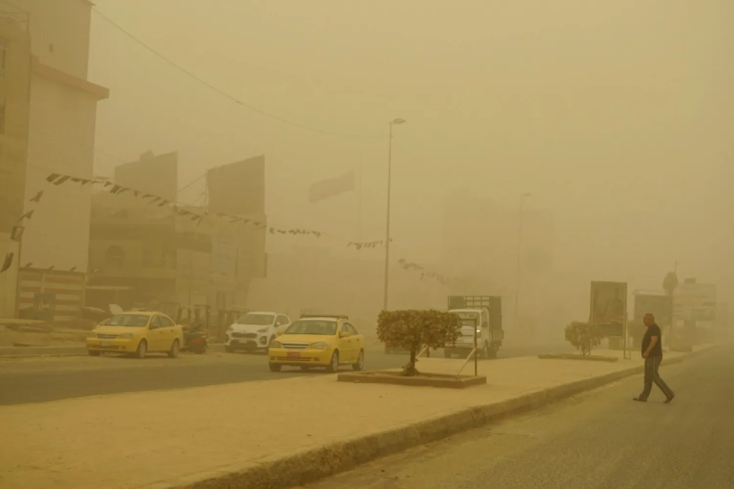 A man crosses a main road during a Spring sandstorm in the Iraqi capital Baghdad on May 5, 2022. (AFP)