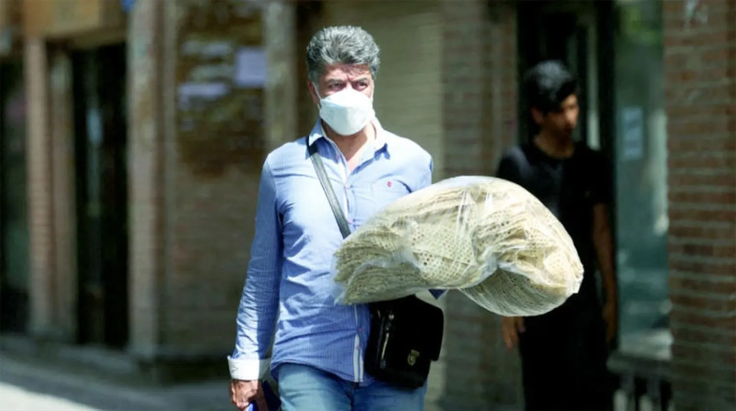 رجل إيراني يحمل الخبز في أحد شوارع طهران الأحد الماضي (رويترز)