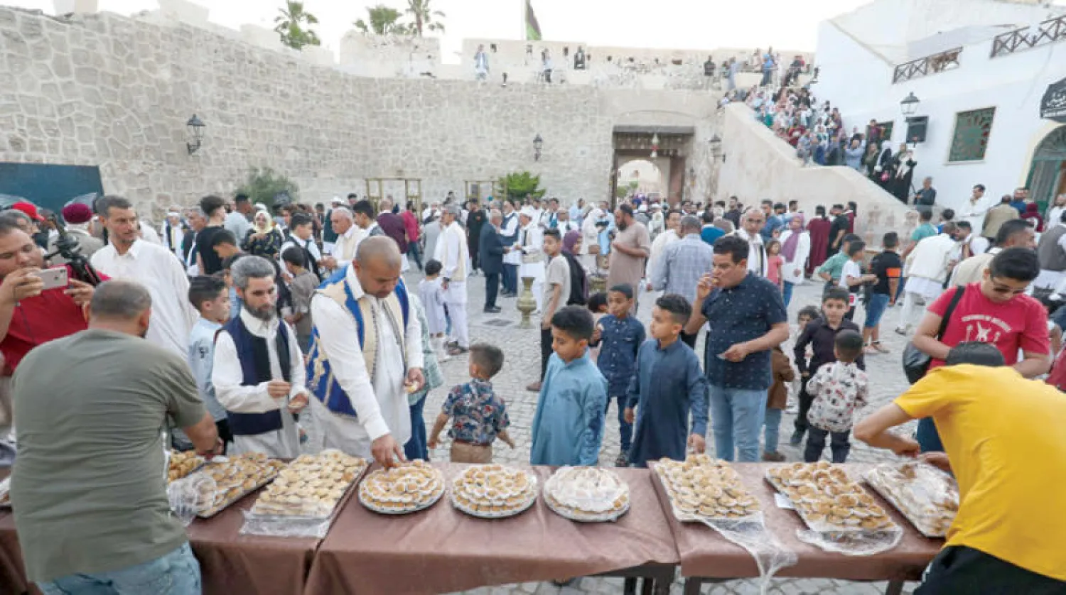 ليبيون يقدمون الحلويات أثناء تجمعهم بالمدينة القديمة في طرابلس أول من أمس (أ.ف.ب)