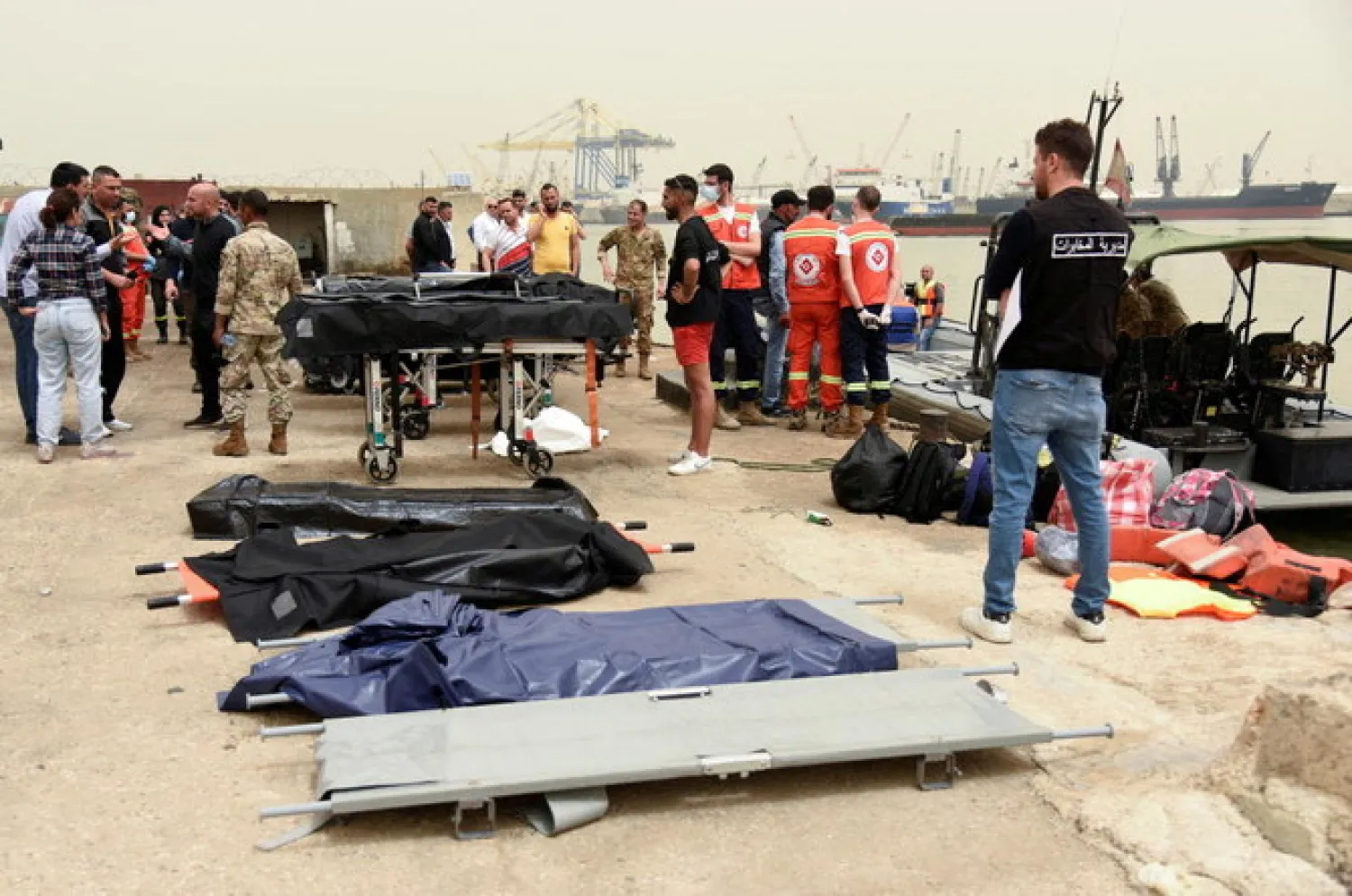 People stand near stretchers that are prepared for dead bodies after a boat capsized off the Lebanese coast of Tripoli overnight, at port of Tripoli, northern Lebanon April 24, 2022. (Reuters)
