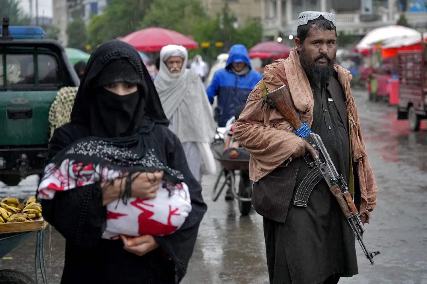 A Taliban fighter stands guard as people walk through the old market, in the city of Kabul, Afghanistan, Tuesday, May 3, 2022. (AP)