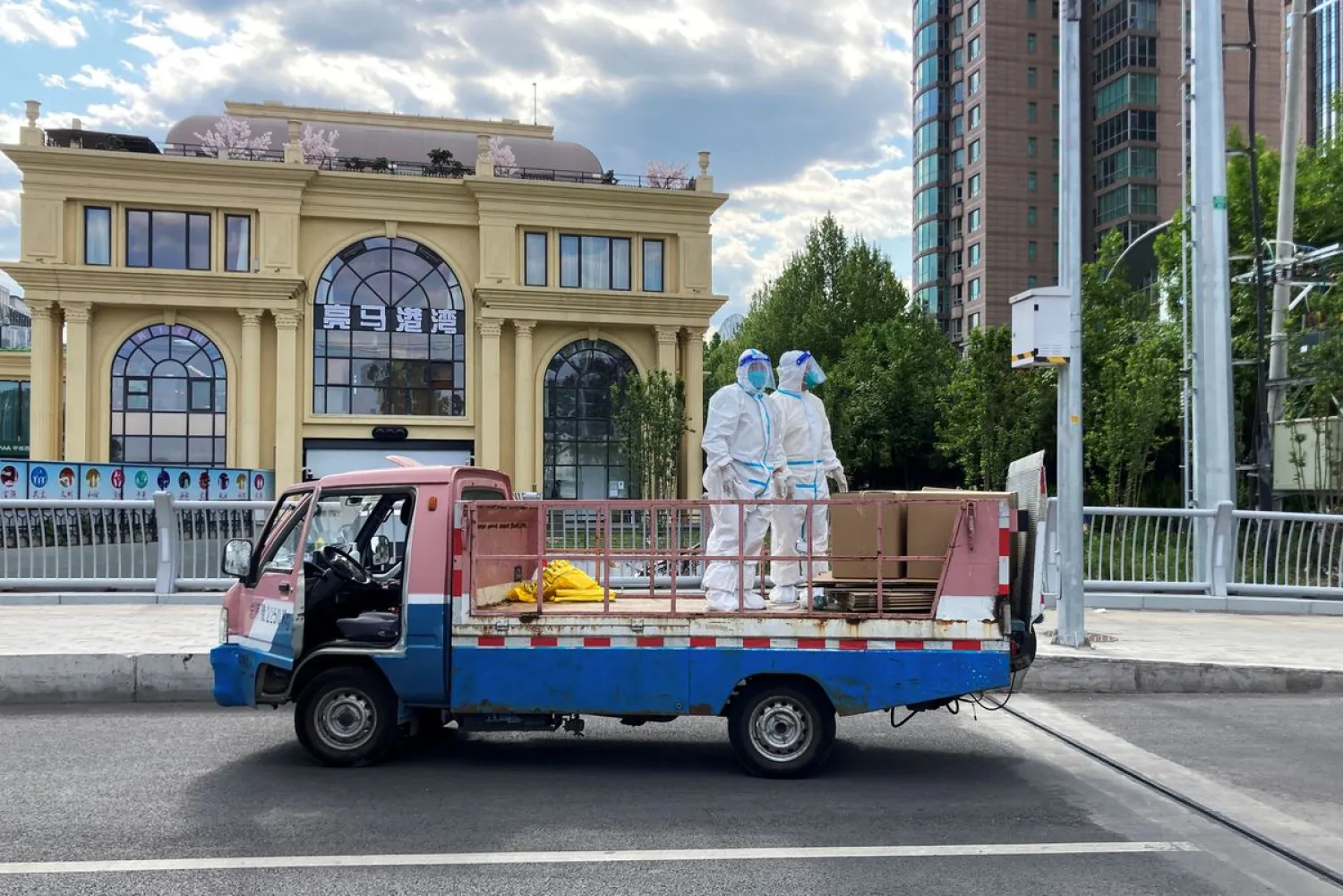 Workers in protective suits stand in a truck on a street in Beijing, China. Reuters