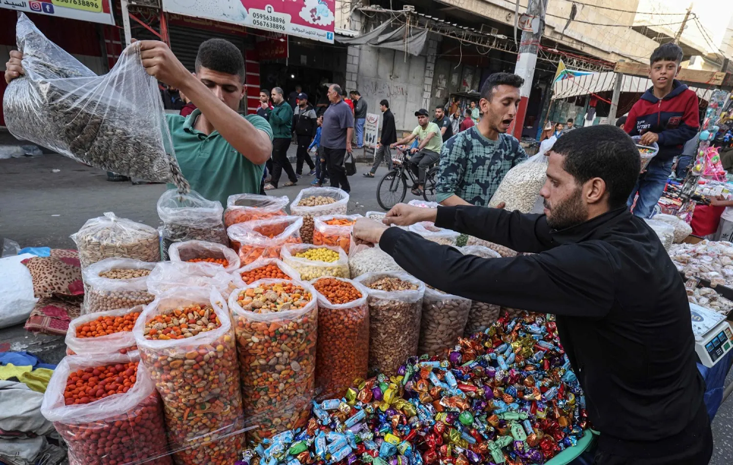 Vendors replenish their stock as Palestinians shop at a market in Rafah in the southern Gaza Strip, on May 1, 2022, on the eve of Eid al-Fitr which marks the end of the Muslim fasting month of Ramadan. (AFP)