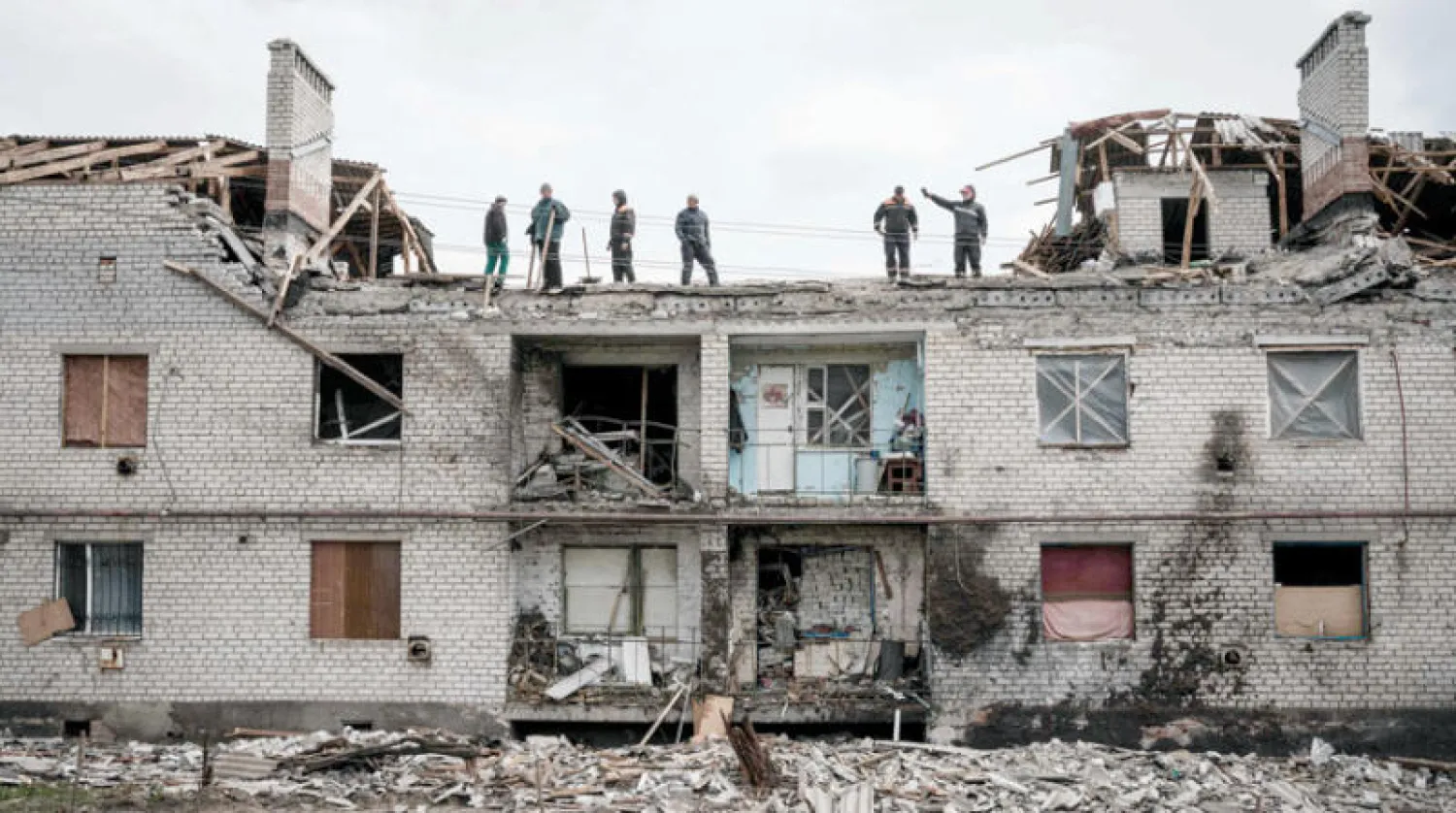 عاملون يتفقدون أمس مبنى تعرض للقصف في شيركاسكيه شرق أوكرانيا (أ.ف.ب)