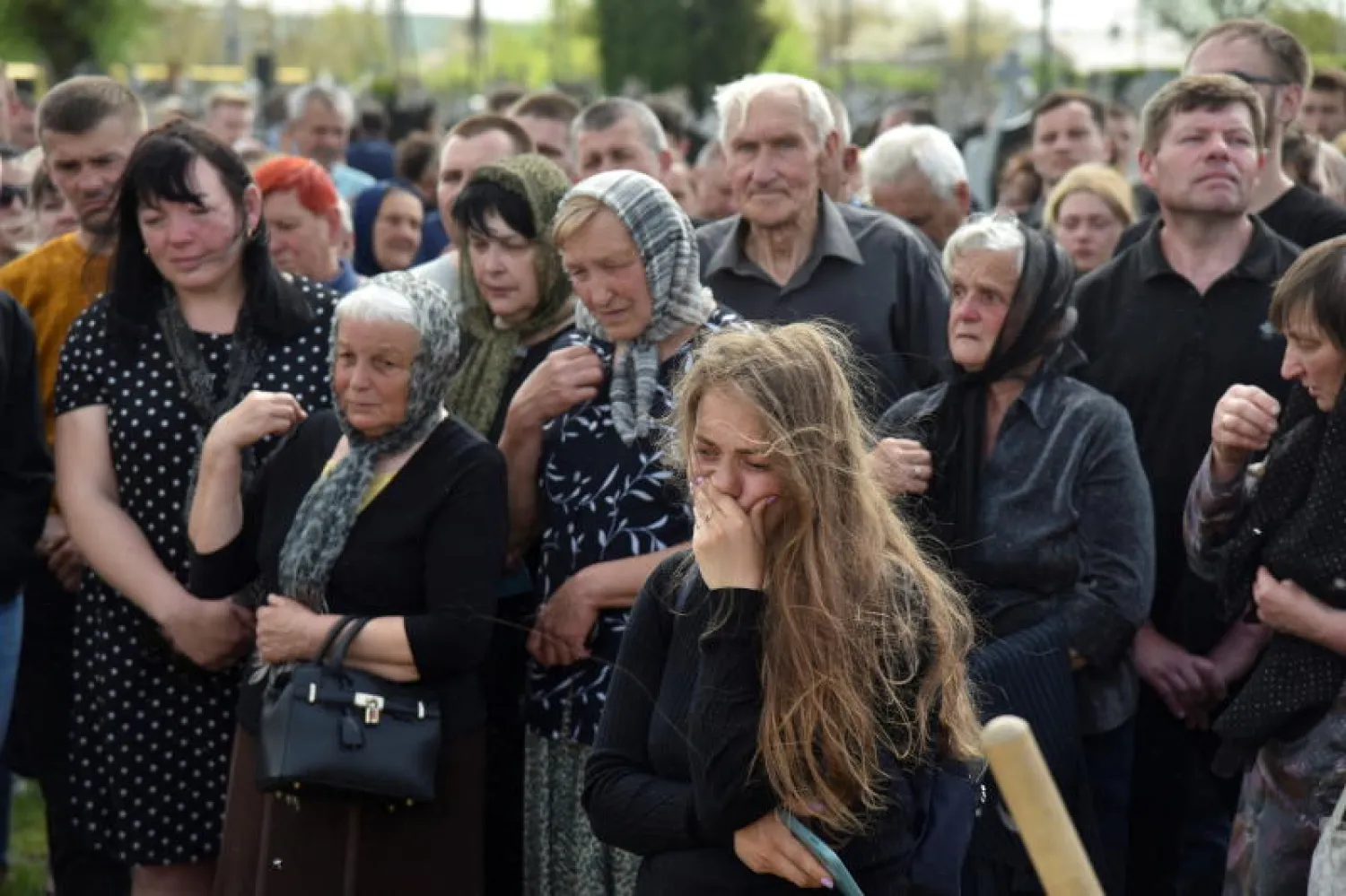 أشخاص يحضرون جنازة شخص قتل بالقرب من بلدة زولوتي بمنطقة لوهانسك (رويترز)