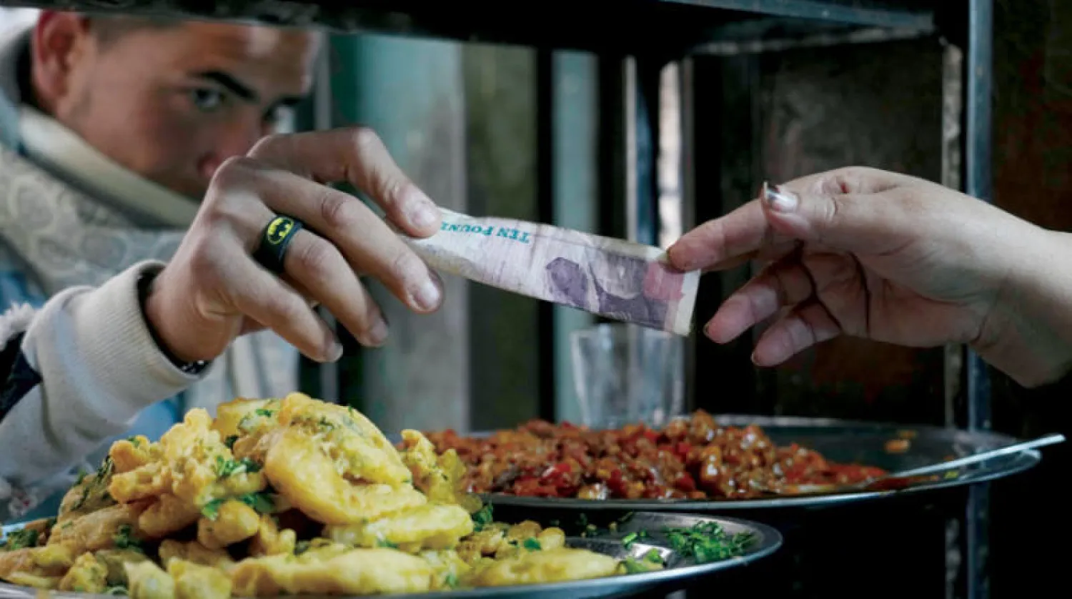 متسوق يدفع عملة نقدية مصرية مقابل شرائه الطعام في القاهرة (أ.ب)