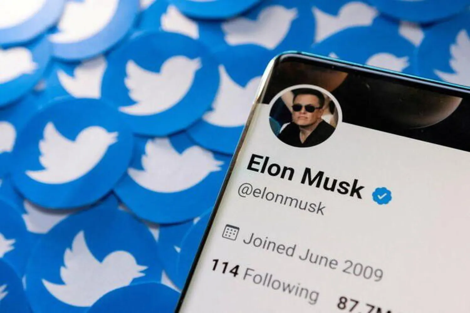 Elon Musk's twitter account is seen on a smartphone in front of the Twitter logo in this photo illustration taken, April 15, 2022. REUTERS/Dado Ruvic/Illustration/File Photo
