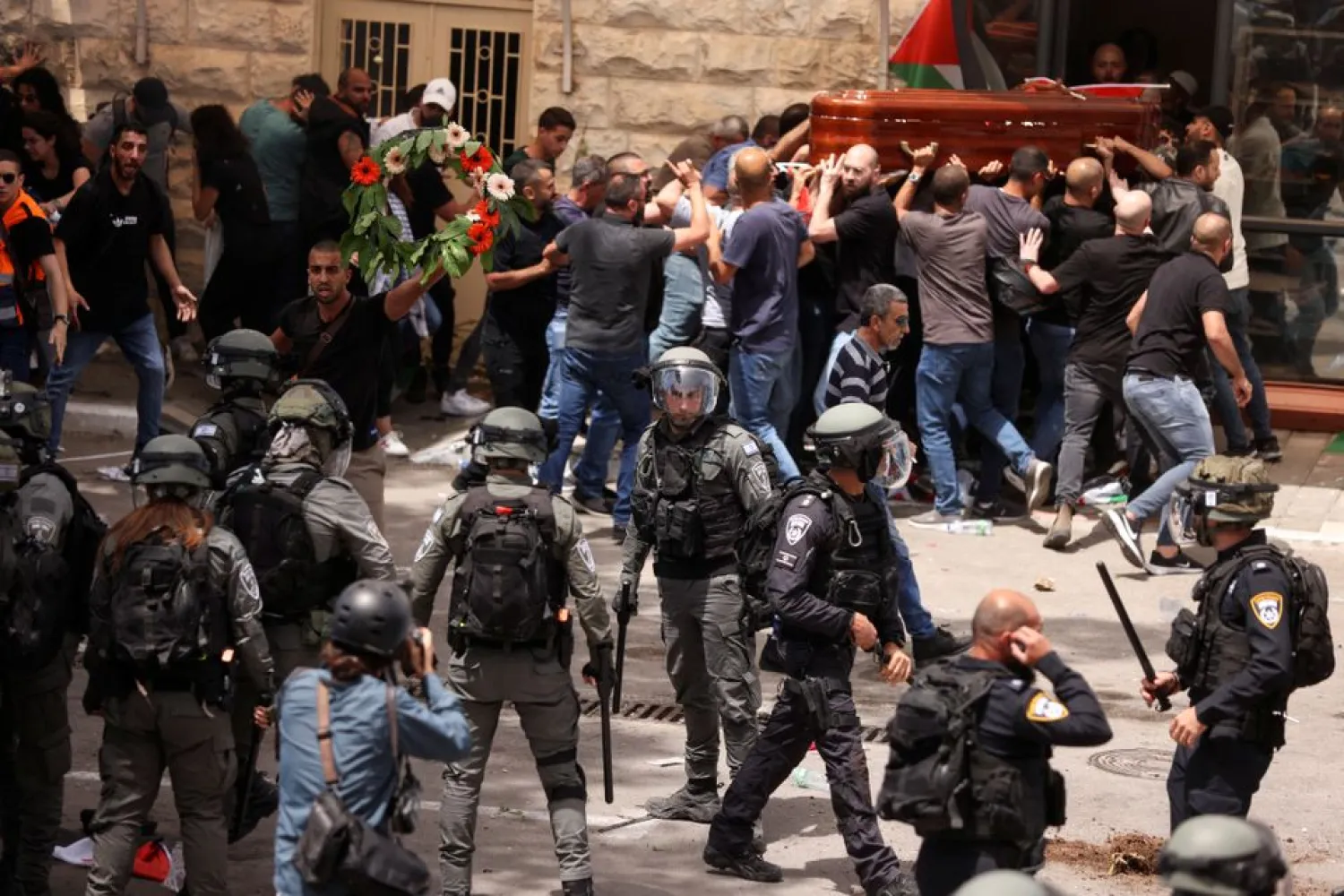 Family and friends carry the coffin of Al Jazeera reporter Shireen Abu Akleh, who was killed during an Israeli raid in Jenin in the occupied West Bank, next to Israeli security forces, during her funeral in Jerusalem, May 13, 2022. REUTERS/Ammar Awad
