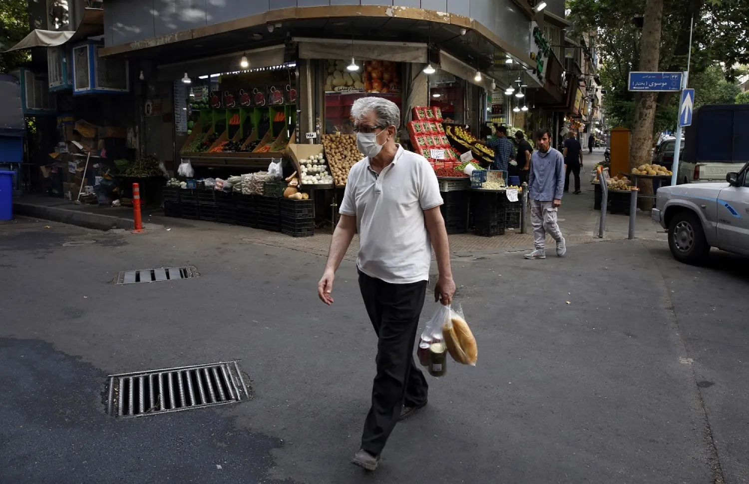 An Iranian man walks with his shopping in a street in Tehran, Iran, 13 May 2022. (EPA)