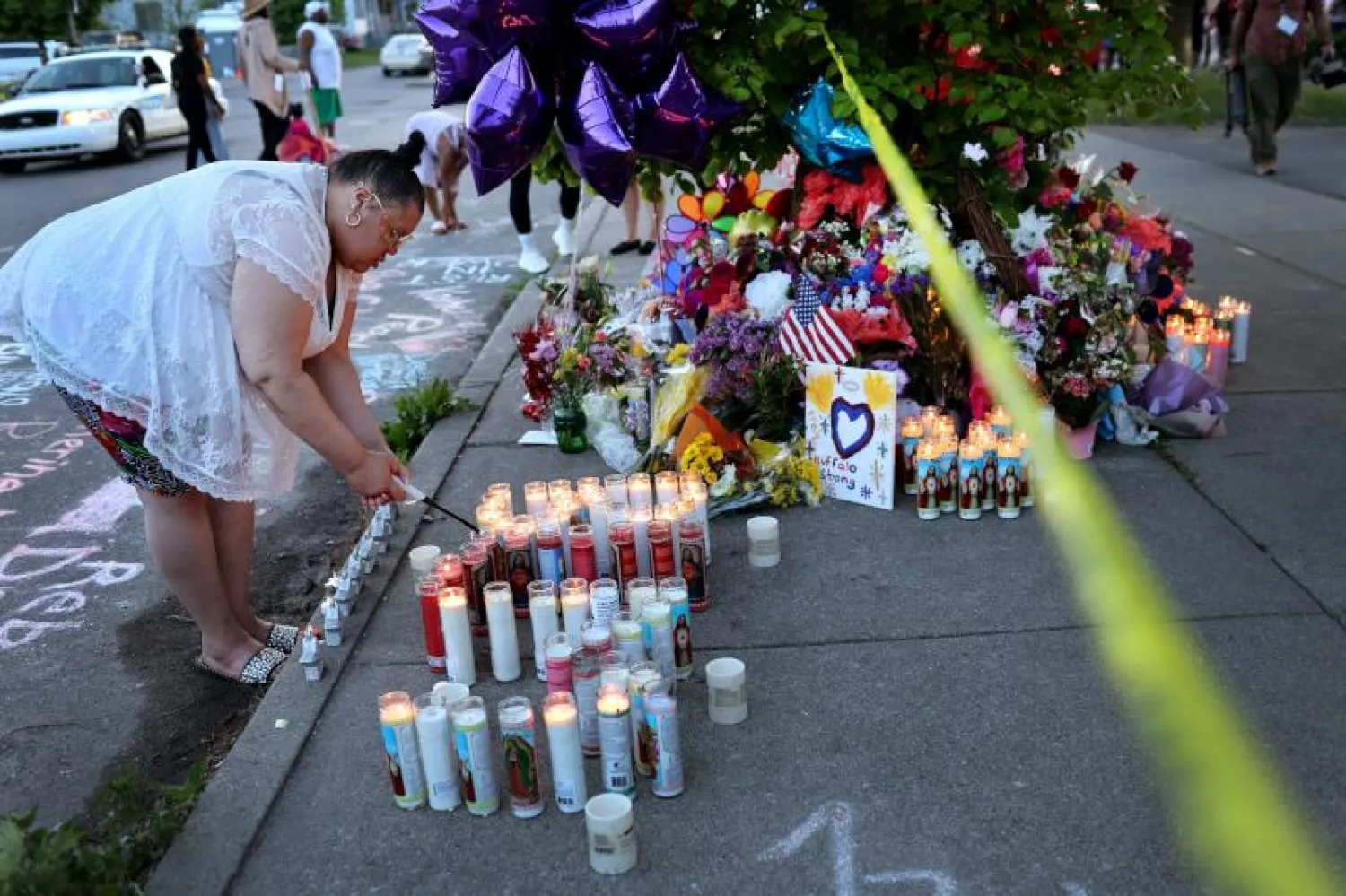 امرأة تضيء شمعة مكان وقوع الجريمة في مدينة بافالو أمس (أ.ف.ب)