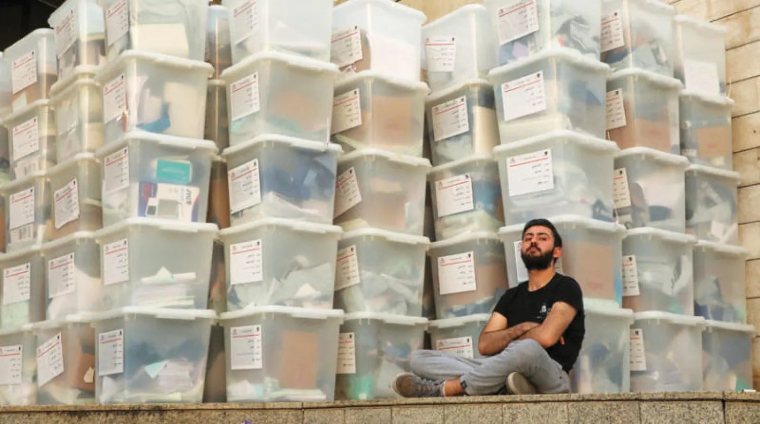 موظف لبناني يستريح قرب مجموعة كبيرة من صناديق الاقتراع (رويترز)