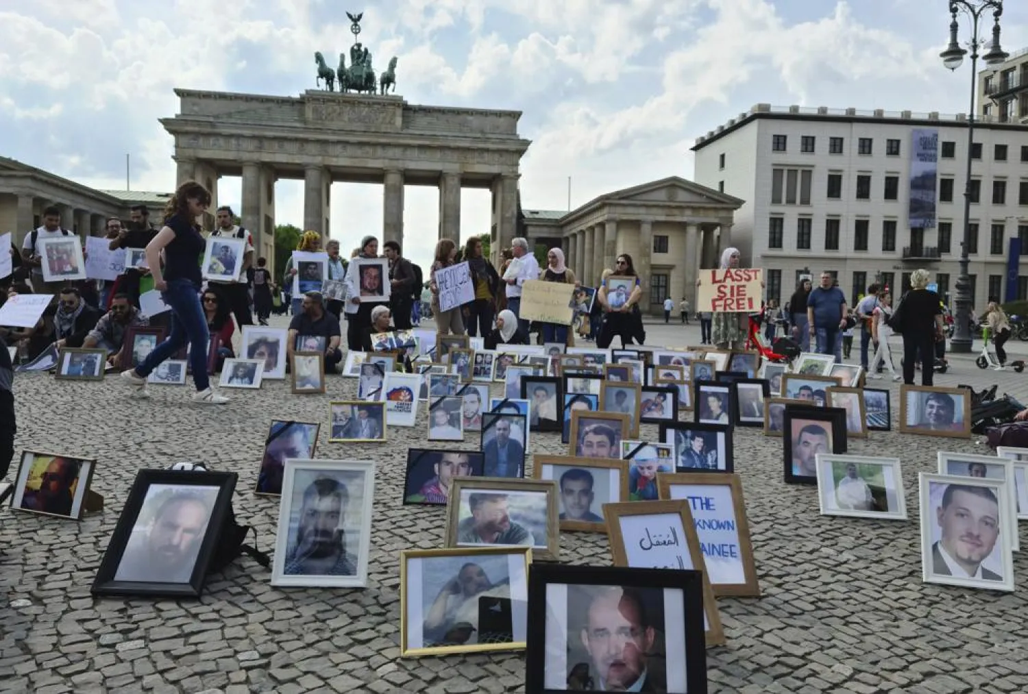 This photo provided by Syrian activist Wafaa Mustafa, shows families of Syrian detainees carrying photos of their detained the missing loved ones, as they demanding their freedom and the revealing of their fate and whereabouts during a sit-in, in Berlin Germany, on Saturday, May, 7, 2022. (Wafaa Mustafa, via AP)