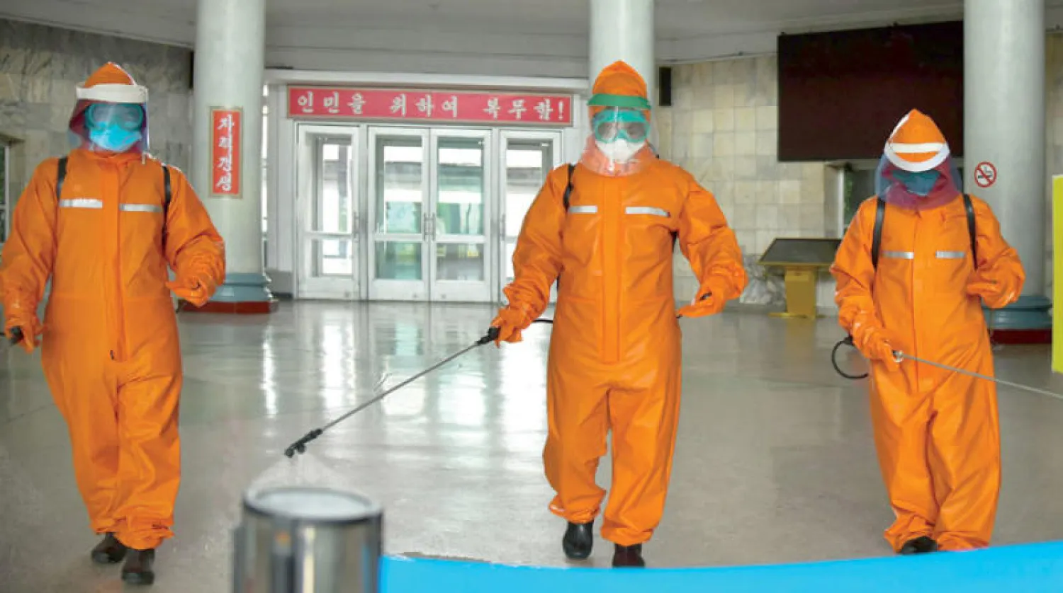 صورة وزعتها وكالة أنباء كوريا الشمالية لرجال يعقمون محطة في بيونغ يانغ (إ.ب.أ)