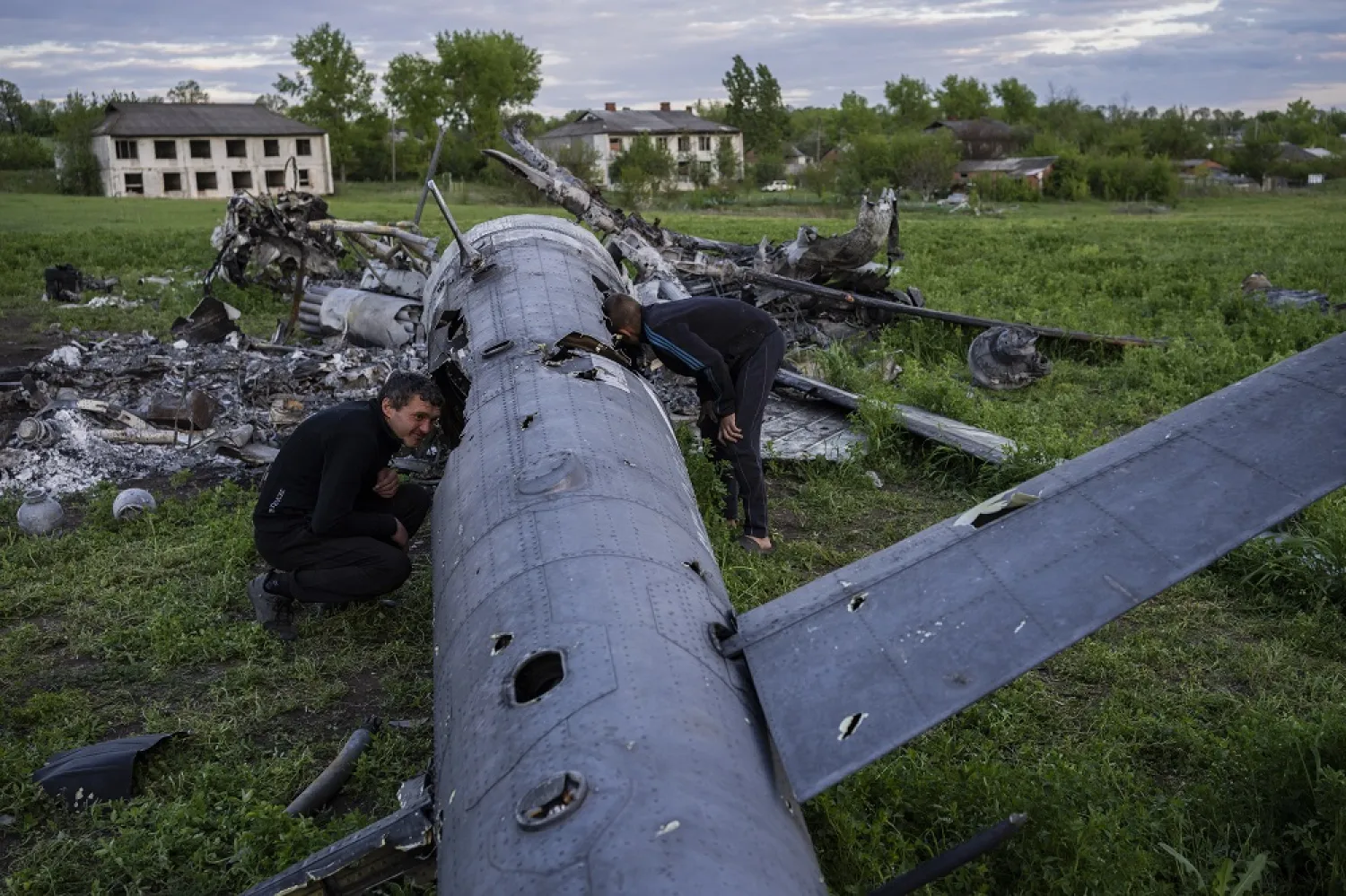 Oleksiy Polyakov, right, and Roman Voitko check the remains of a destroyed Russian helicopter that lies in a field in the village of Malaya Rohan, Kharkiv region, Ukraine, Monday, May 16, 2022. (AP)
