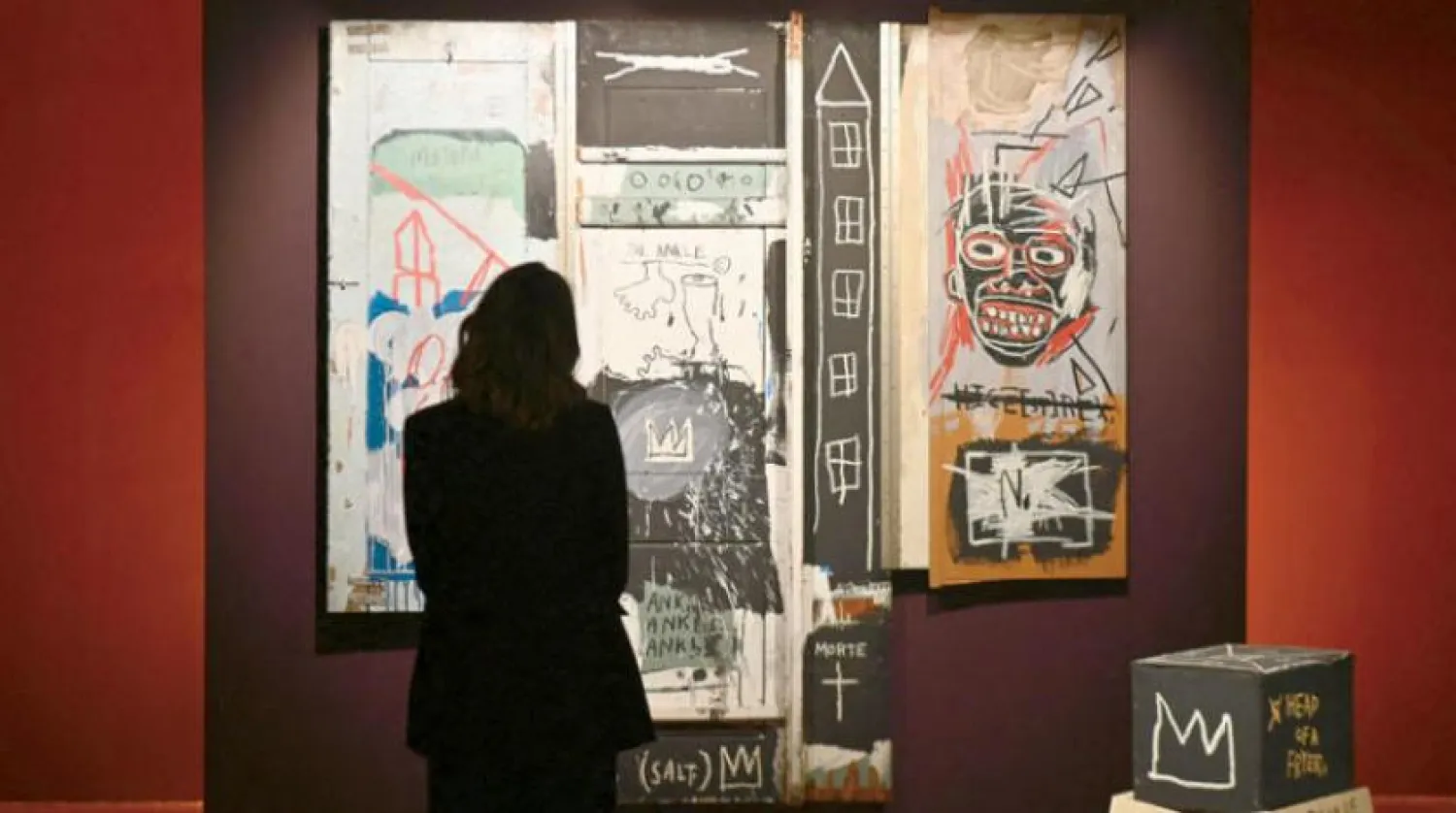 Ressam Jean- Michel Basquiat’ın tablosunu izleyen bir sanatsever (AFP)