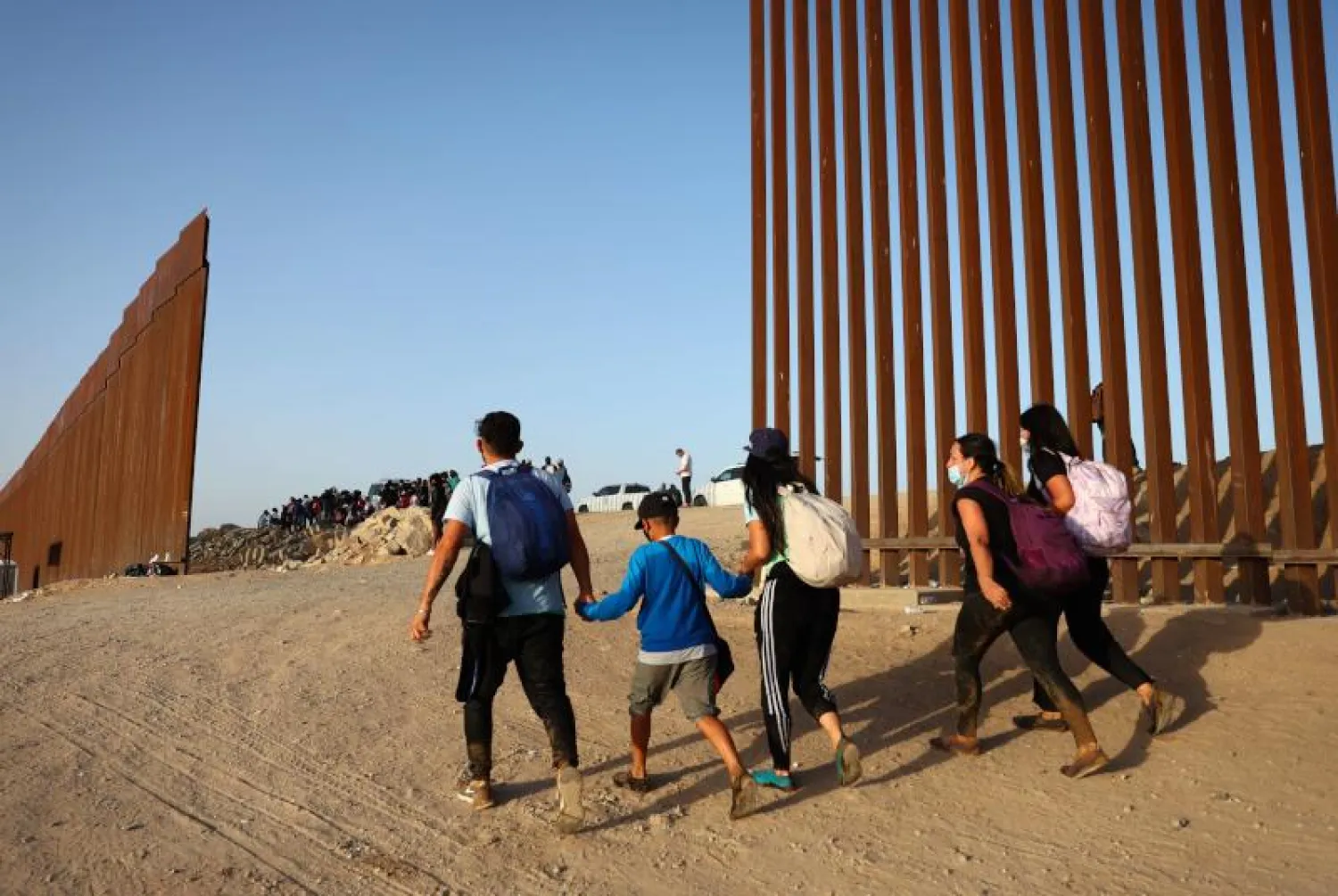 مهاجرون غير قانونيين يعبرون الحدود بين المكسيك وولاية أريزونا الأميركية عبر فراغ في الجدار الحدودي (أ.ف.ب)