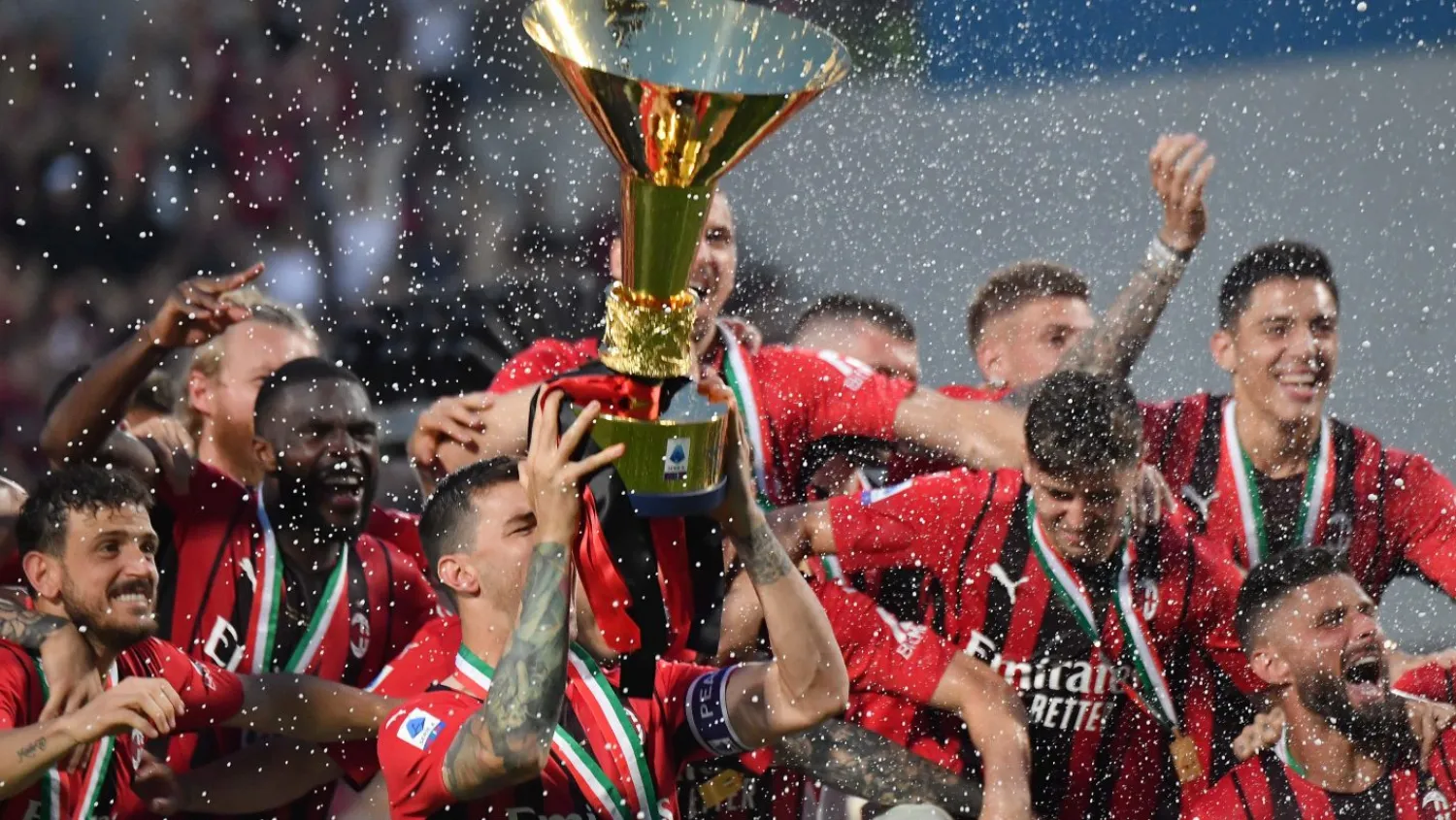 AC Milan’s Italian defender Alessio Romagnoli (C-L), AC Milan’s French forward Olivier Giroud (Bottom R) and AC Milan’s players celebrate with the winner’s trophy after AC Milan won the Italian Serie A football match between Sassuolo and AC Milan, securing the “Scudetto” championship on May 22, 2022 at the Mapei – Citta del Tricolore stadium in Sassuolo. (Photo by Tiziana FABI / AFP)

