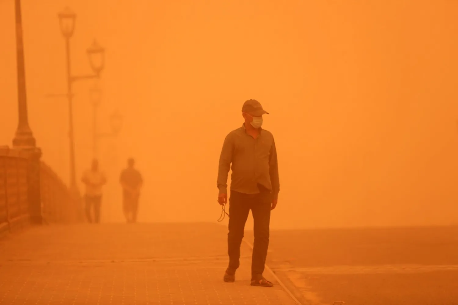 An Iraqi man walks over the al-Shuhadaa bridge shrouded in heavy dust in central Baghdad, Iraq, 23 May 2022. (EPA)