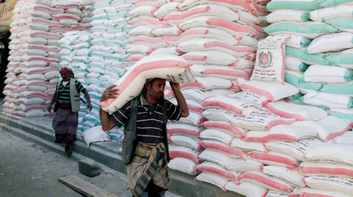 عامل يحمل كيساً من دقيق القمح خارج متجر في صنعاء (رويترز)